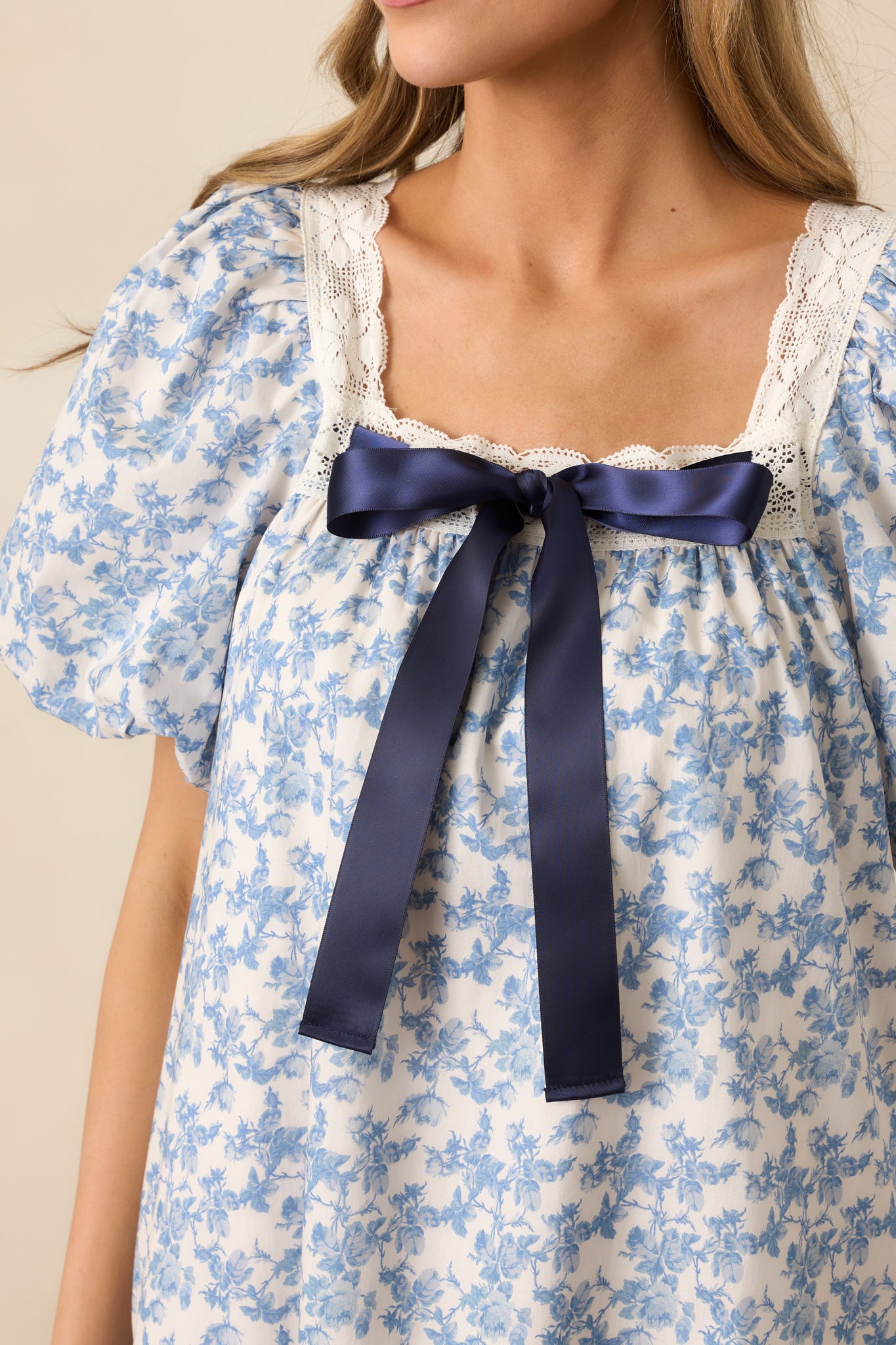 A detailed shot of the lace trim and puff sleeves on the blue mini dress, showcasing the intricate design and soft, feminine textures.