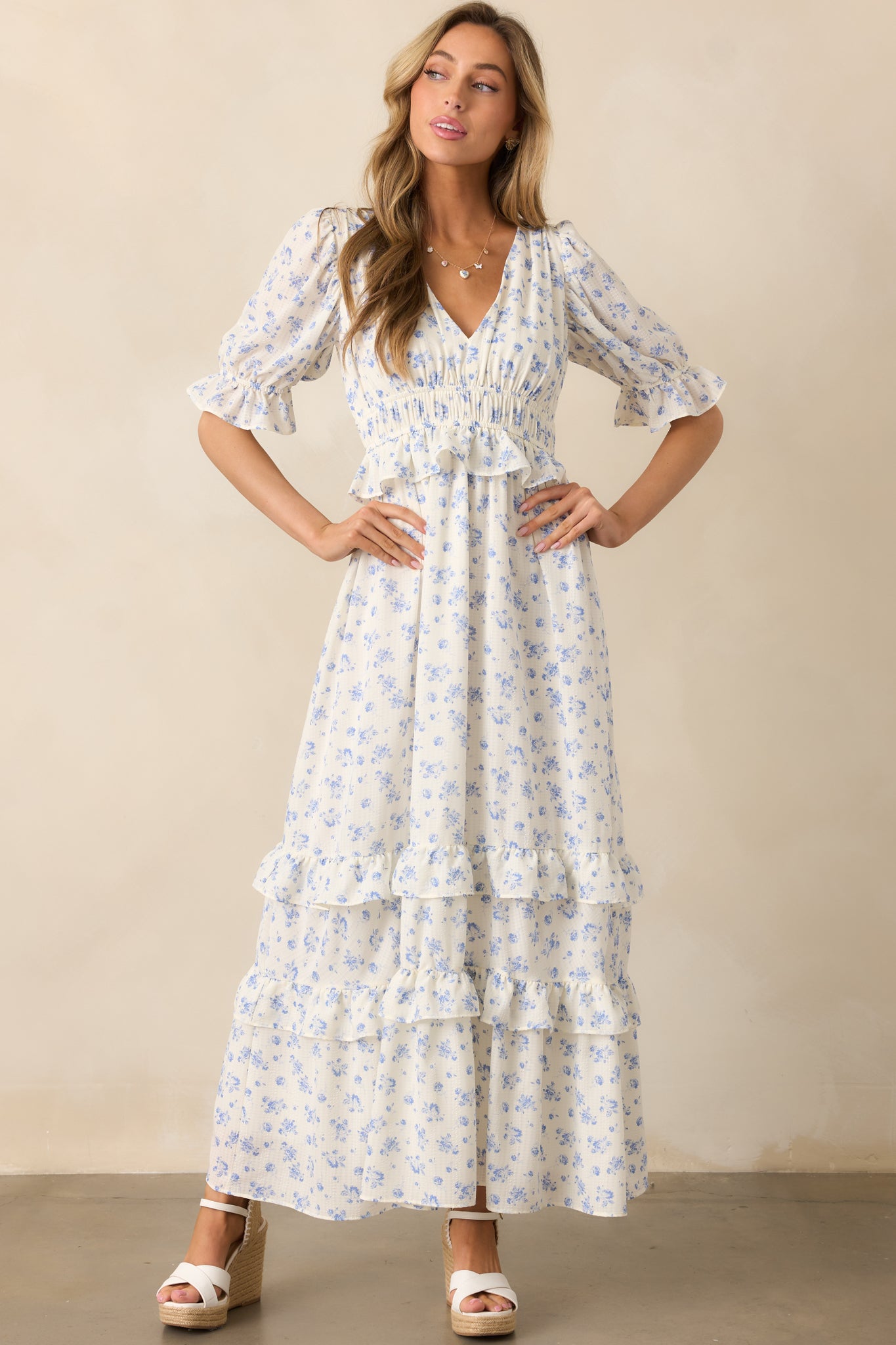  A charming ivory dress with a blue floral pattern, designed with an elastic waistband and ruffled elastic cuffs for a flattering fit.