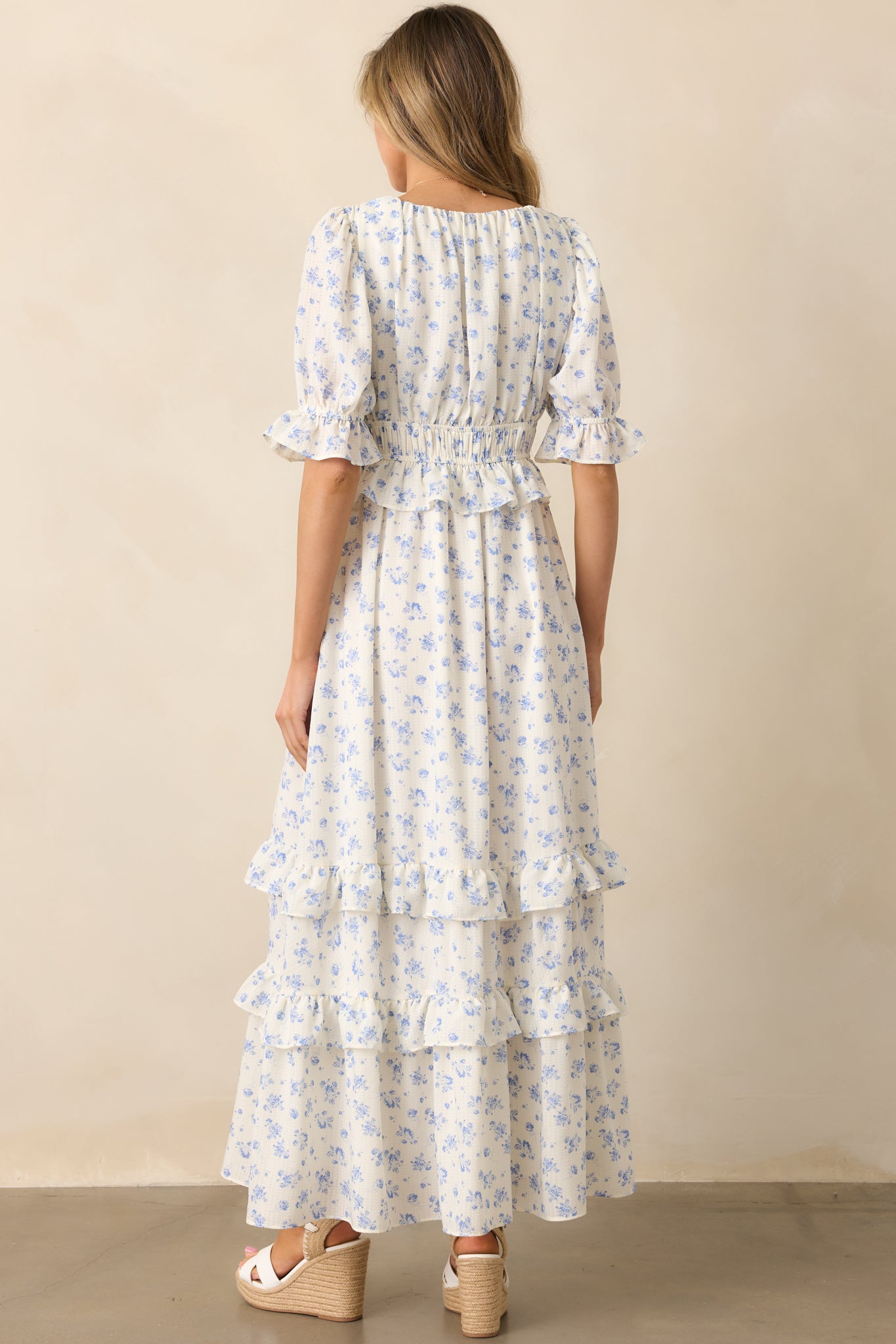 A back view of the ivory dress, showcasing the continuation of the blue floral pattern and soft ruffle detailing.