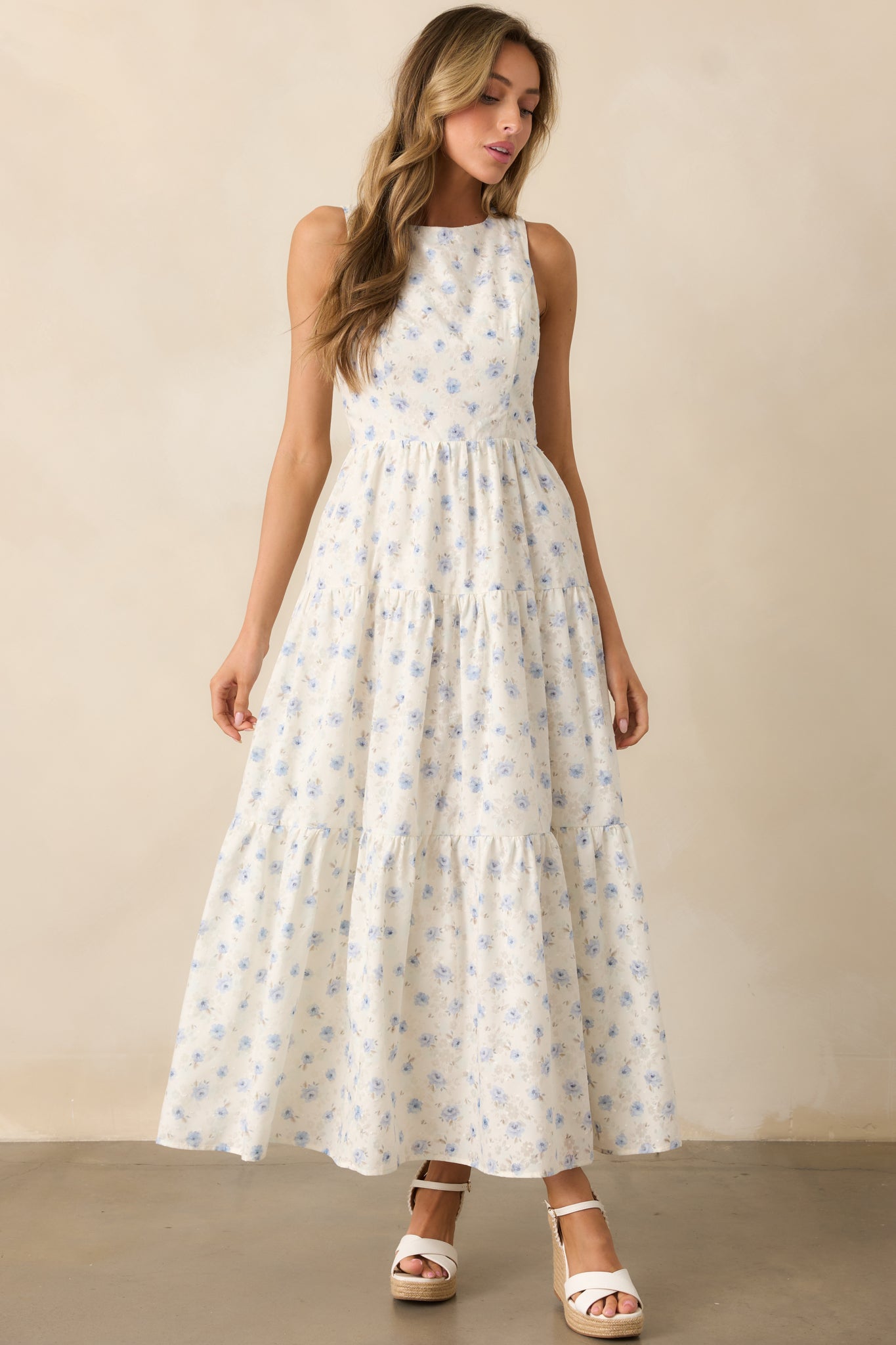 A charming ivory dress with a blue floral pattern, featuring a tiered skirt and a relaxed yet elegant fit.