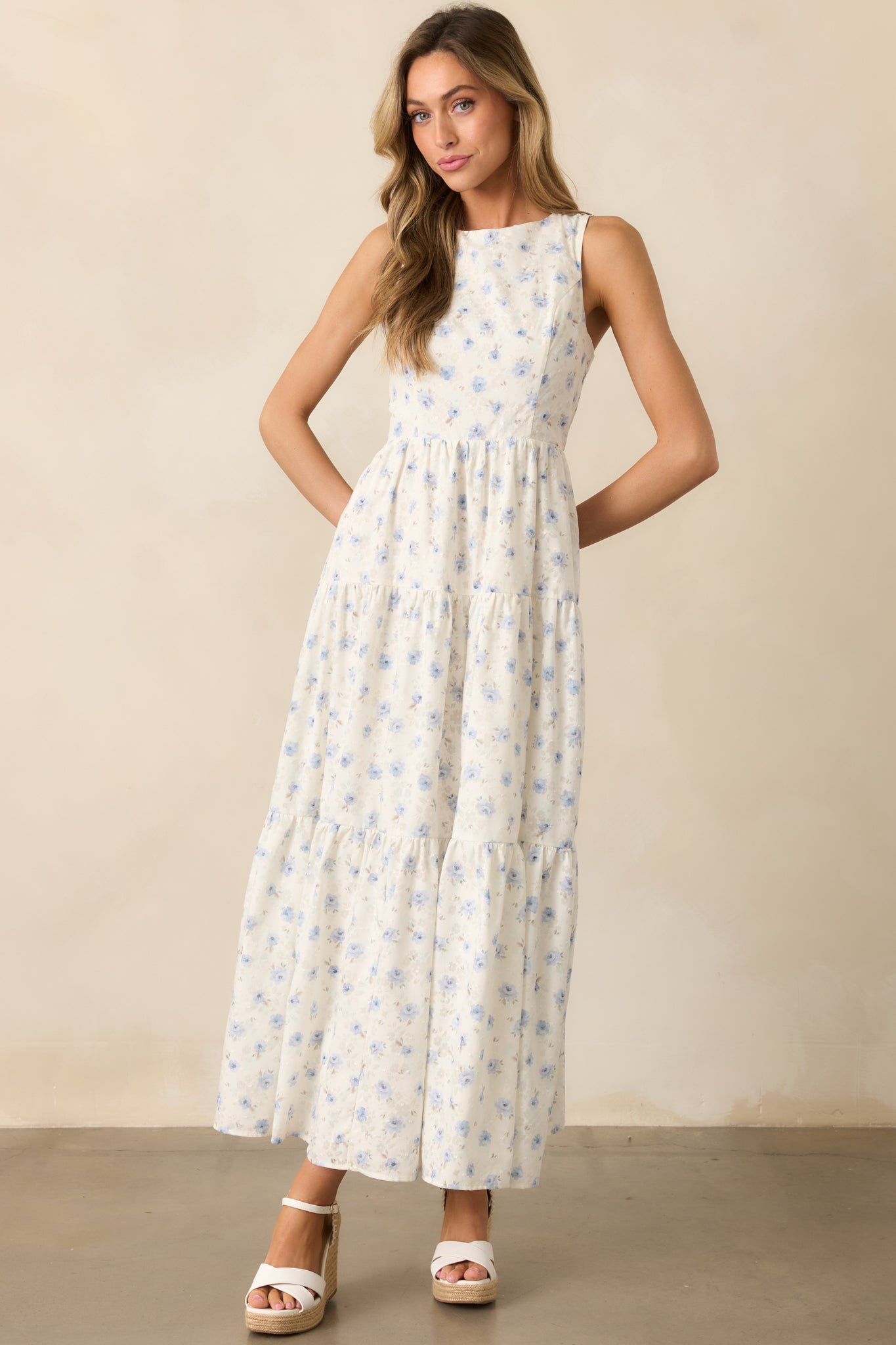  A lightweight ivory dress with blue floral detailing, designed with a round neckline and a flowing three-tiered silhouette.