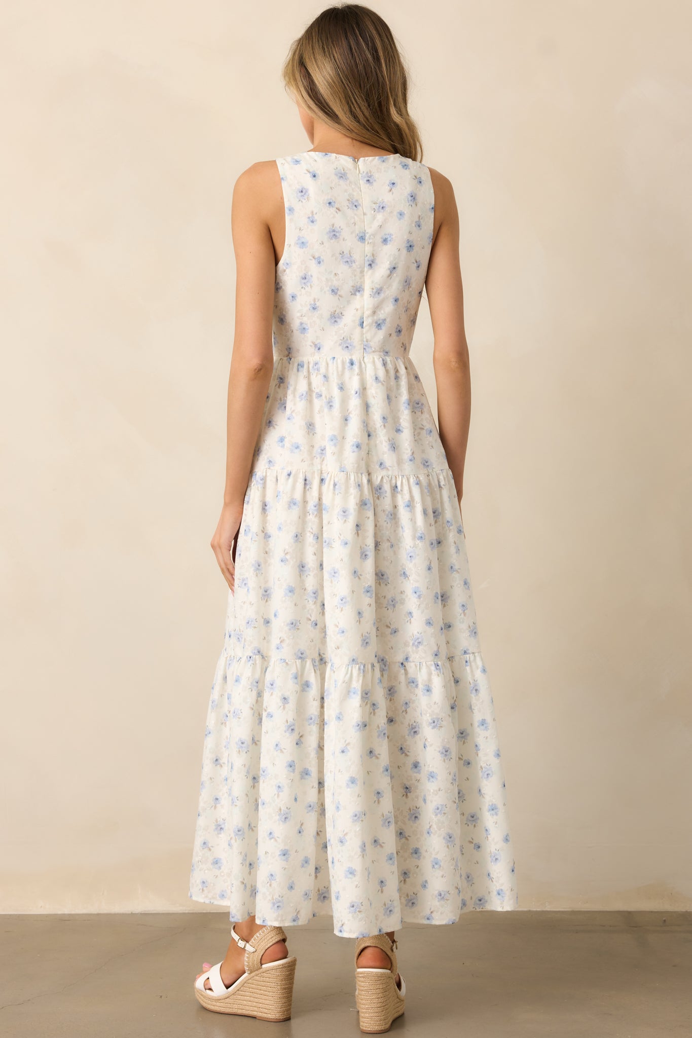 A back view of the ivory dress, highlighting the functional back zipper and the continuation of the blue floral pattern.