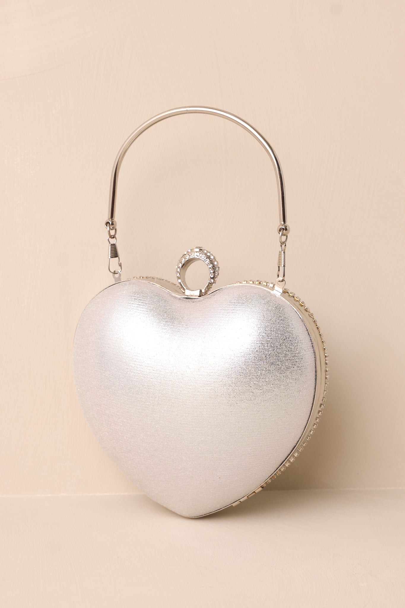 The metallic silver back of the heart-shaped clutch, highlighting its smooth finish and subtle curvature.