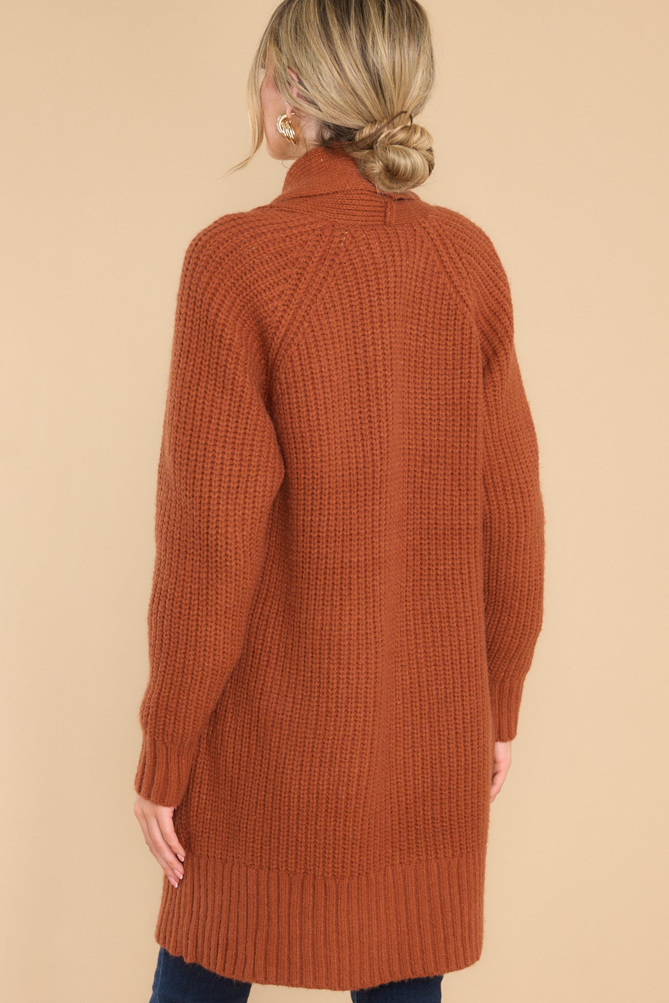 Back view of  this cardigan that features a folded neckline that extends down the front, functional pockets, and a knit texture throughout.