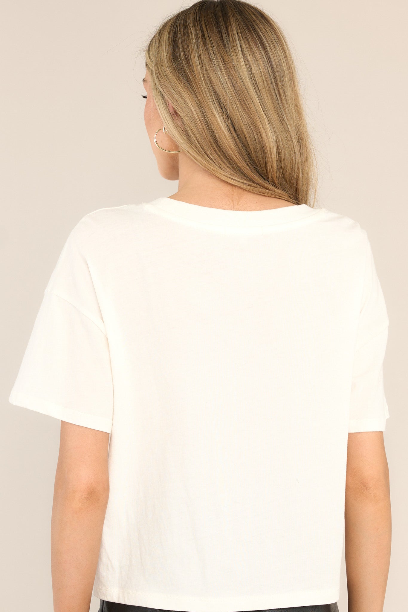 Back view of this tee that features a crew neckline, dropped shoulders, a festive graphic, and a split hemline. 