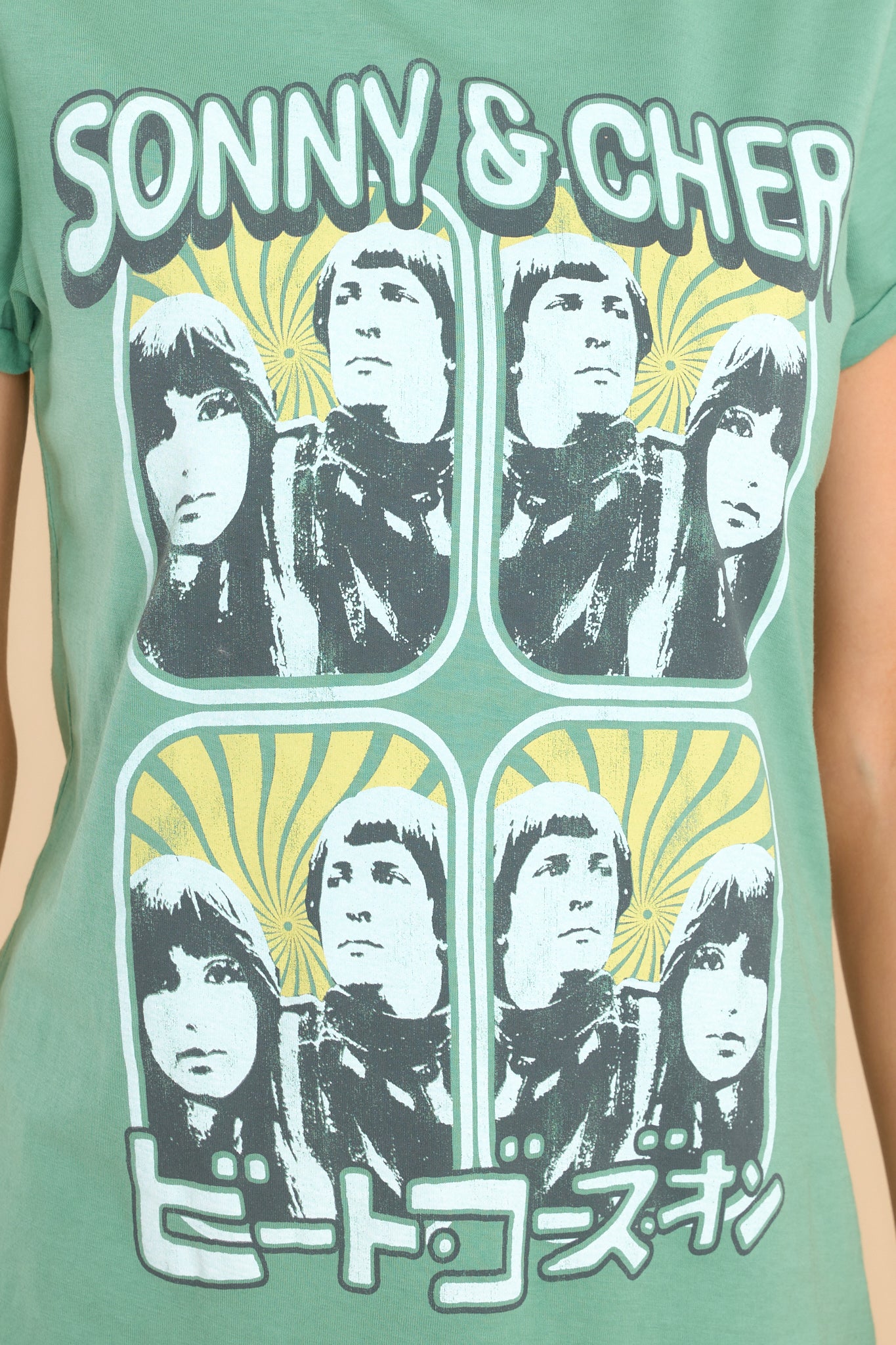 Close up view of this tee that features a graphic on the front of pictures of Sonny and Cher and says "SONNY & CHER" along with a foreign language.