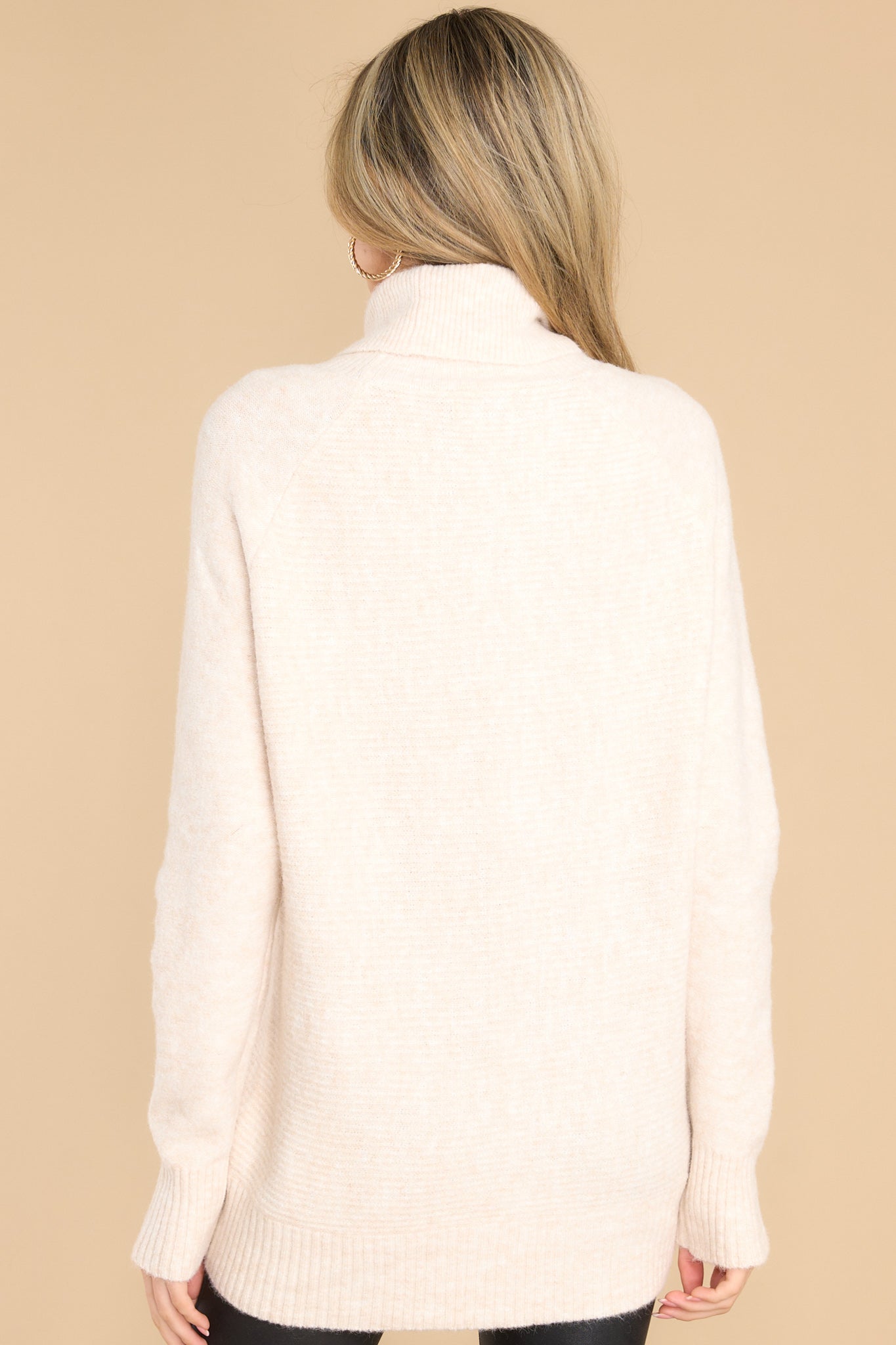 Back view of this sweater that features a cowl turtle neckline, long sleeves with ribbed cuffs, and a bottom hem that tapers in around the hips.