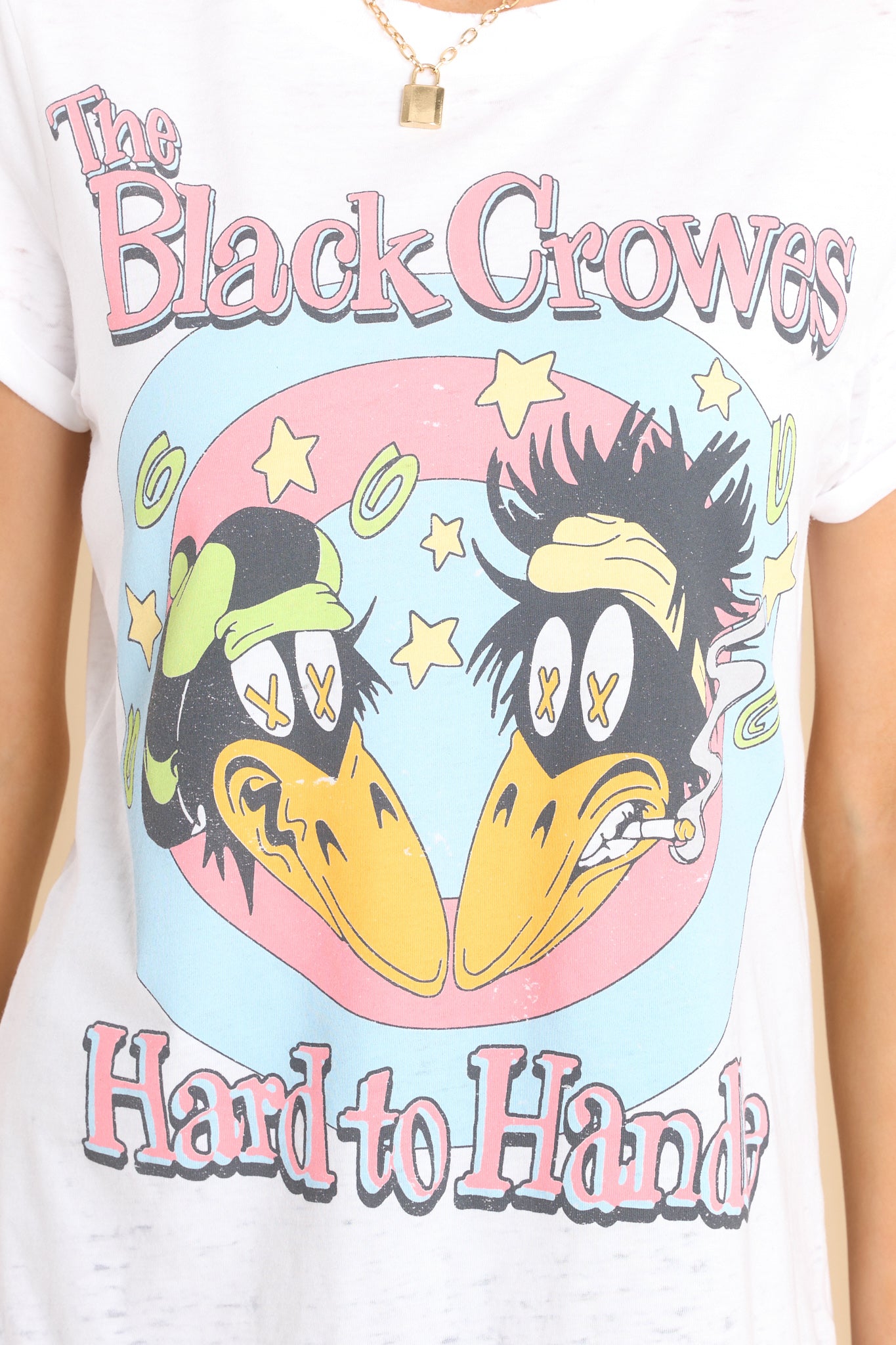 Close up view of this tee that features a round ribbed neckline and folded sleeves, and a graphic of The Black Crowes that says "The Black Crowes" and "Hard to Handle."