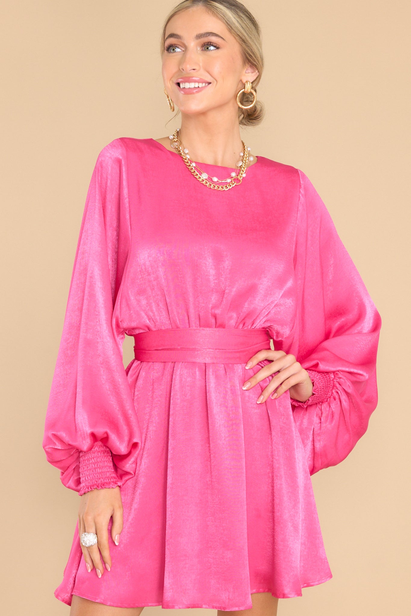 Front view of this dress that features a round neckline, a keyhole with a button closure on the back, flowy sleeves with smocked cuffs, an elastic waistband, a self-tie, and a flowy skirt.