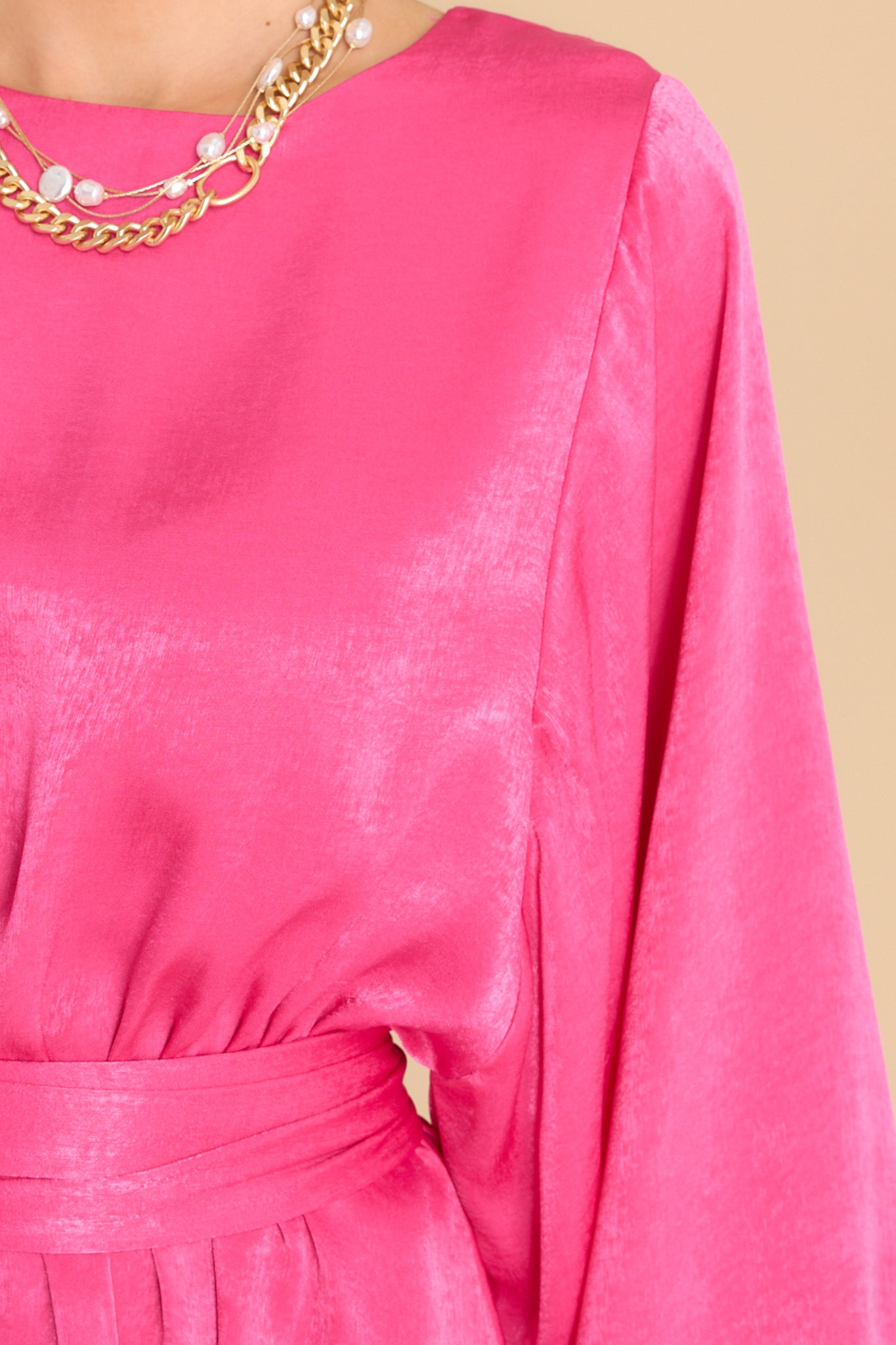 Close up view of this dress that features a round neckline, a keyhole with a button closure on the back, flowy sleeves with smocked cuffs, an elastic waistband, a self-tie, and a flowy skirt.