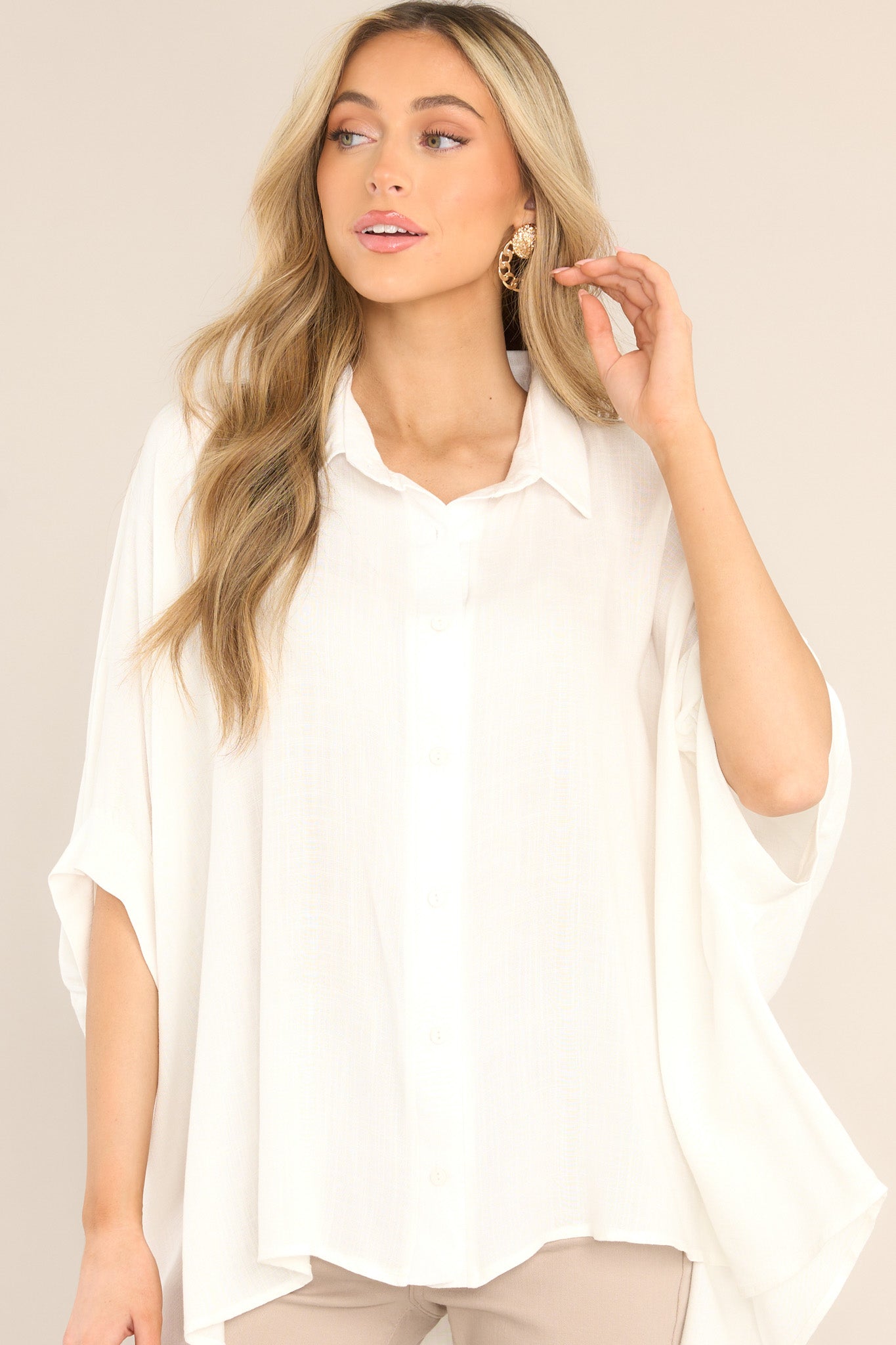 Front view of this top that features a collar neckline, functional buttons down the middle, dolman sleeves, and a long fit.