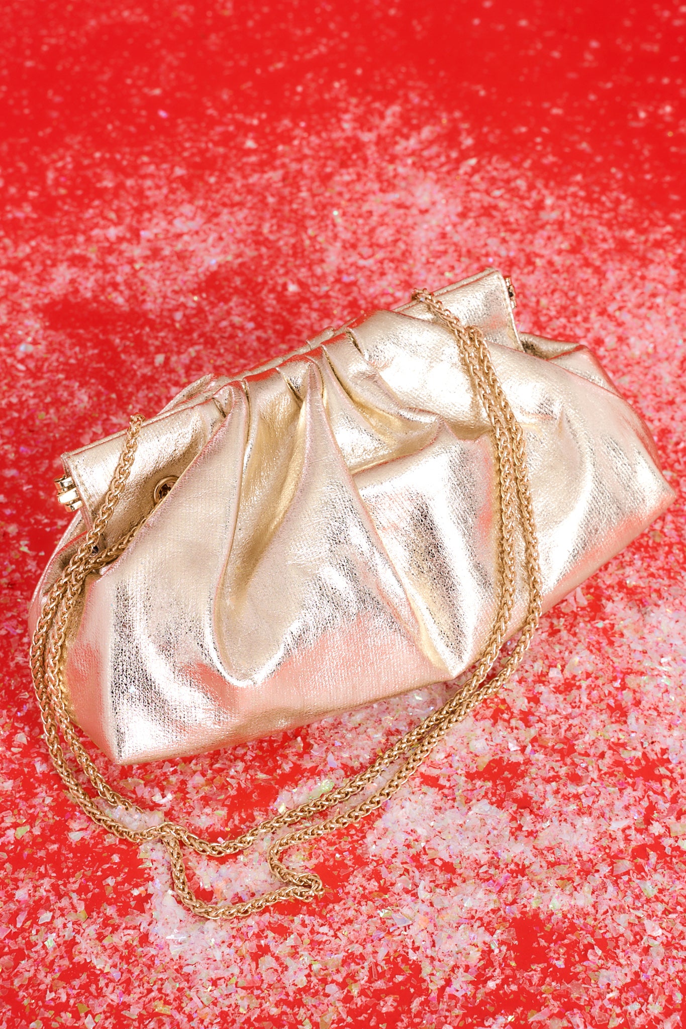 Top view of this bag that features a wide hinged opening that snaps shut (no zipper or snap button closure) , a non-removable gold chain strap, and one zipper pocket inside.