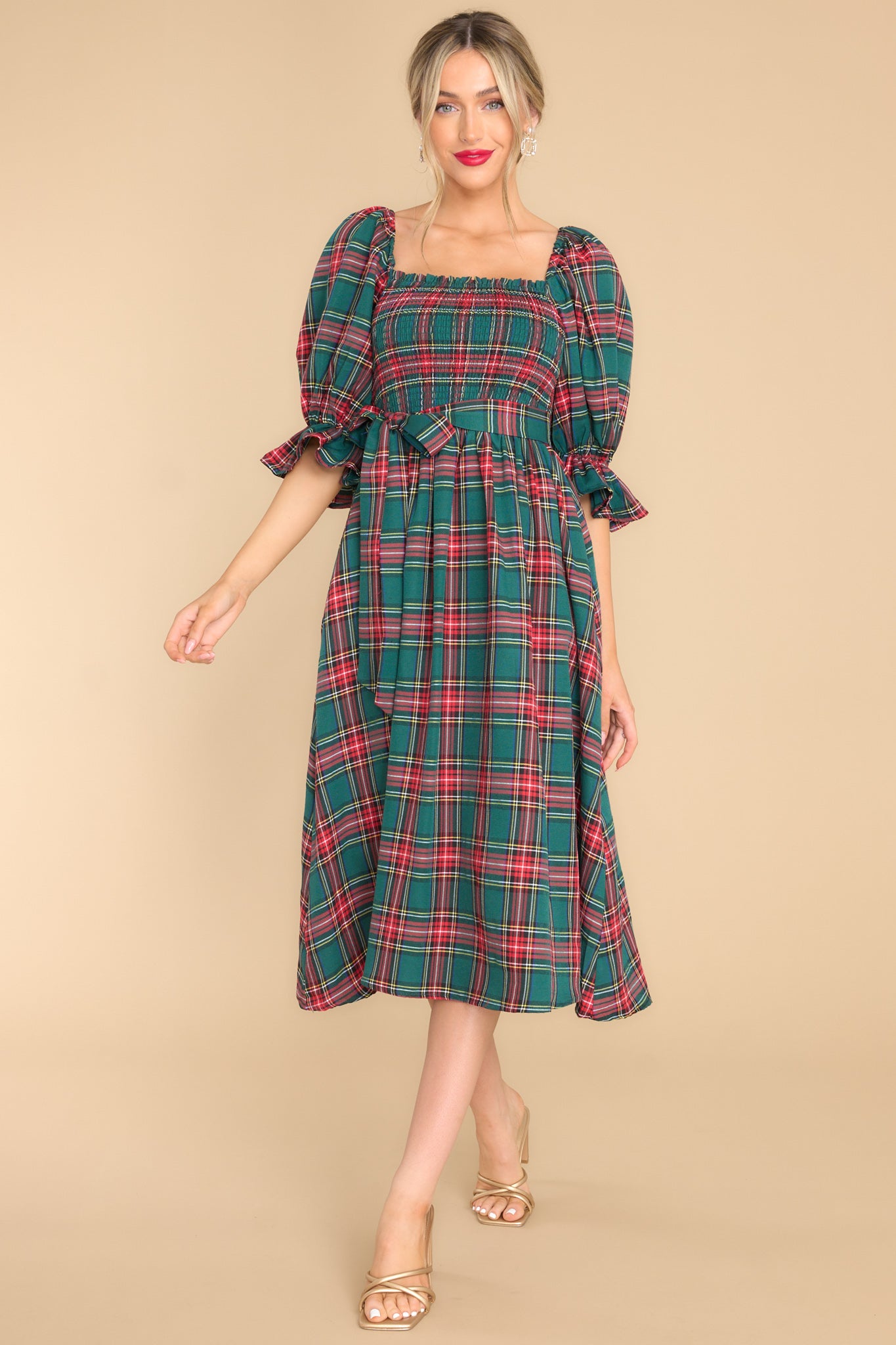 Front, full body photo of precious green plaid dress featuring a square neck, classic midi length, and pockets. 