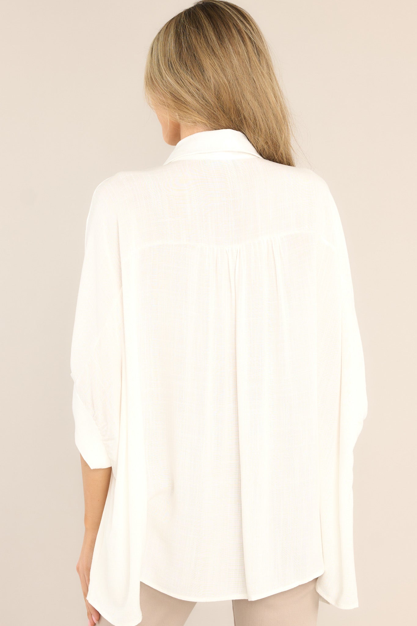 Back view of this top that features a collar neckline, functional buttons down the middle, dolman sleeves, and a long fit.