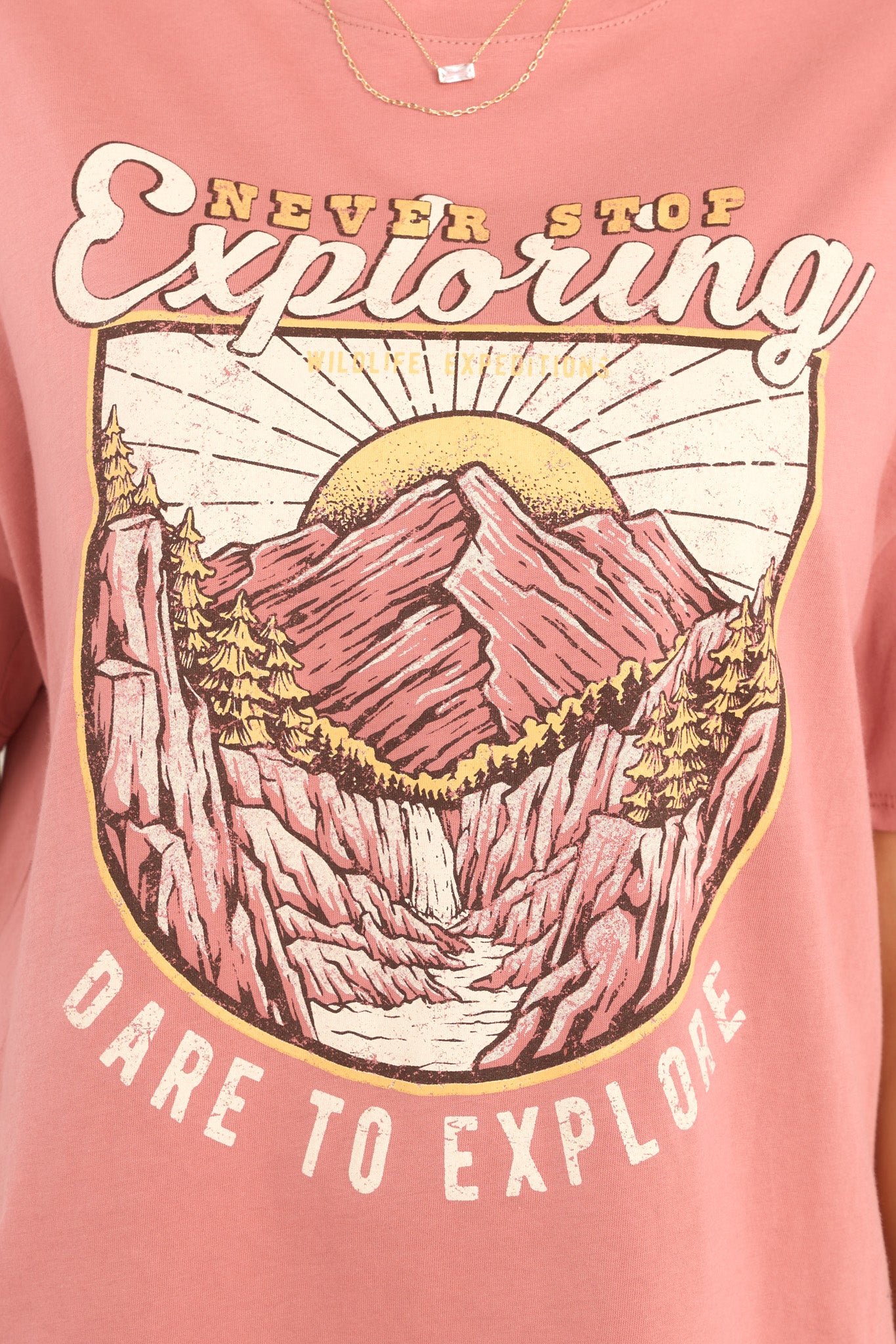 Close up view of this top that features a mountain graphic that says "NEVER STOP Exploring" and "DARE TO EXPLORE."