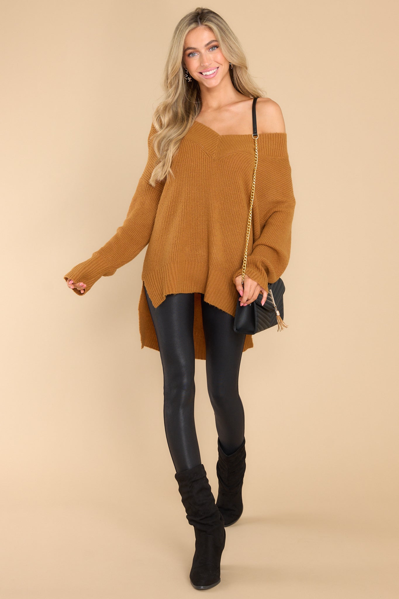 This camel colored sweater features a wide v-neckline, long sleeves with ribbed cuffs, a bottom hem that is longer in the back and has small slits up both sides, and a super soft feel throughout.