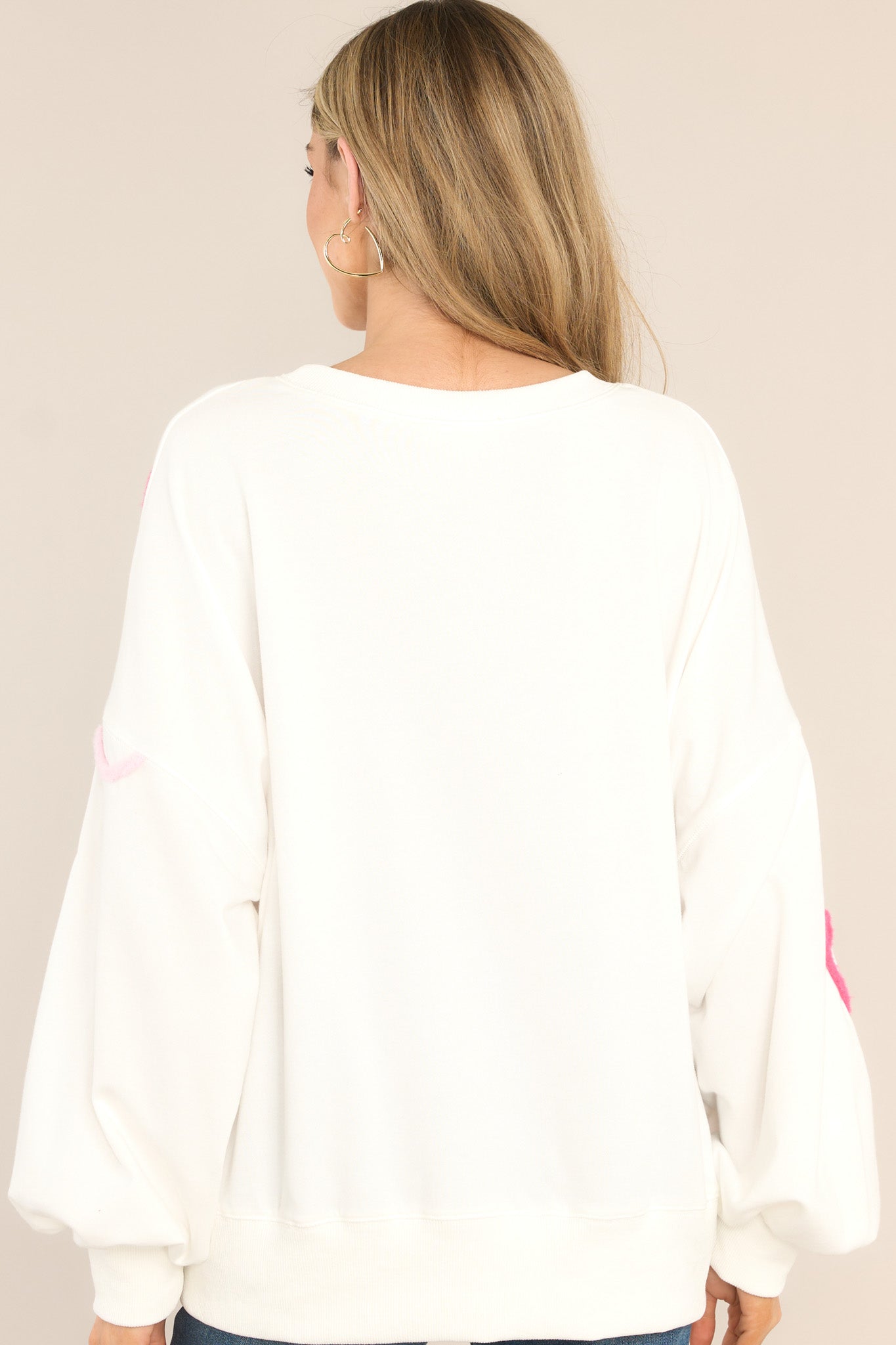 Back view of this sweatshirt that features a crew neckline, textured whimsical heart detailing, ribbed cuffed bishop sleeves, and a ribbed hemline.