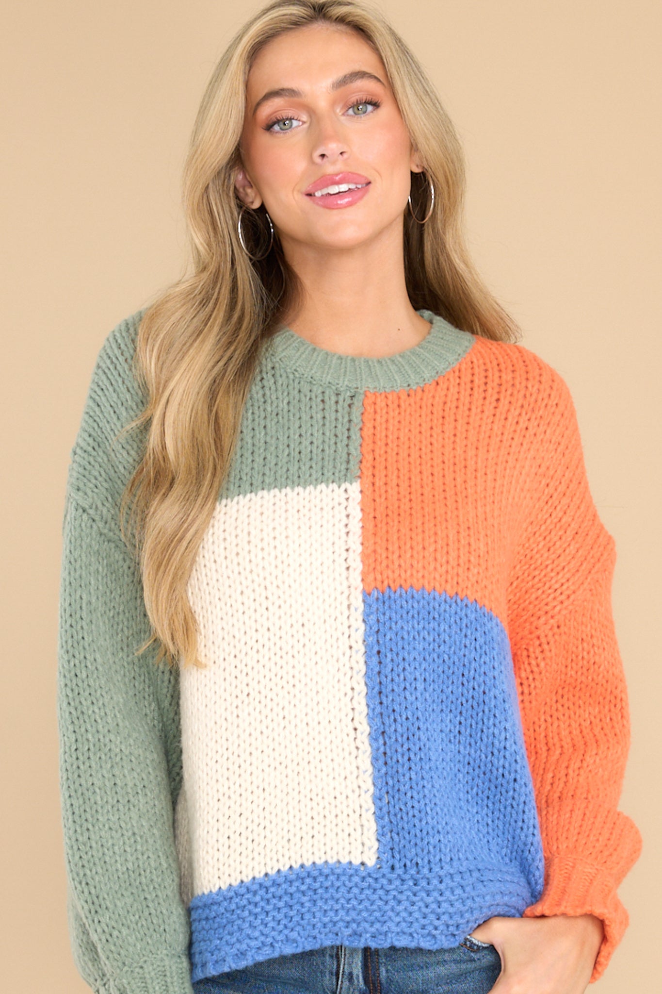 Front view of this sweater that showcases the color-block pattern of the fabric in shades of green, white, orange, and blue.