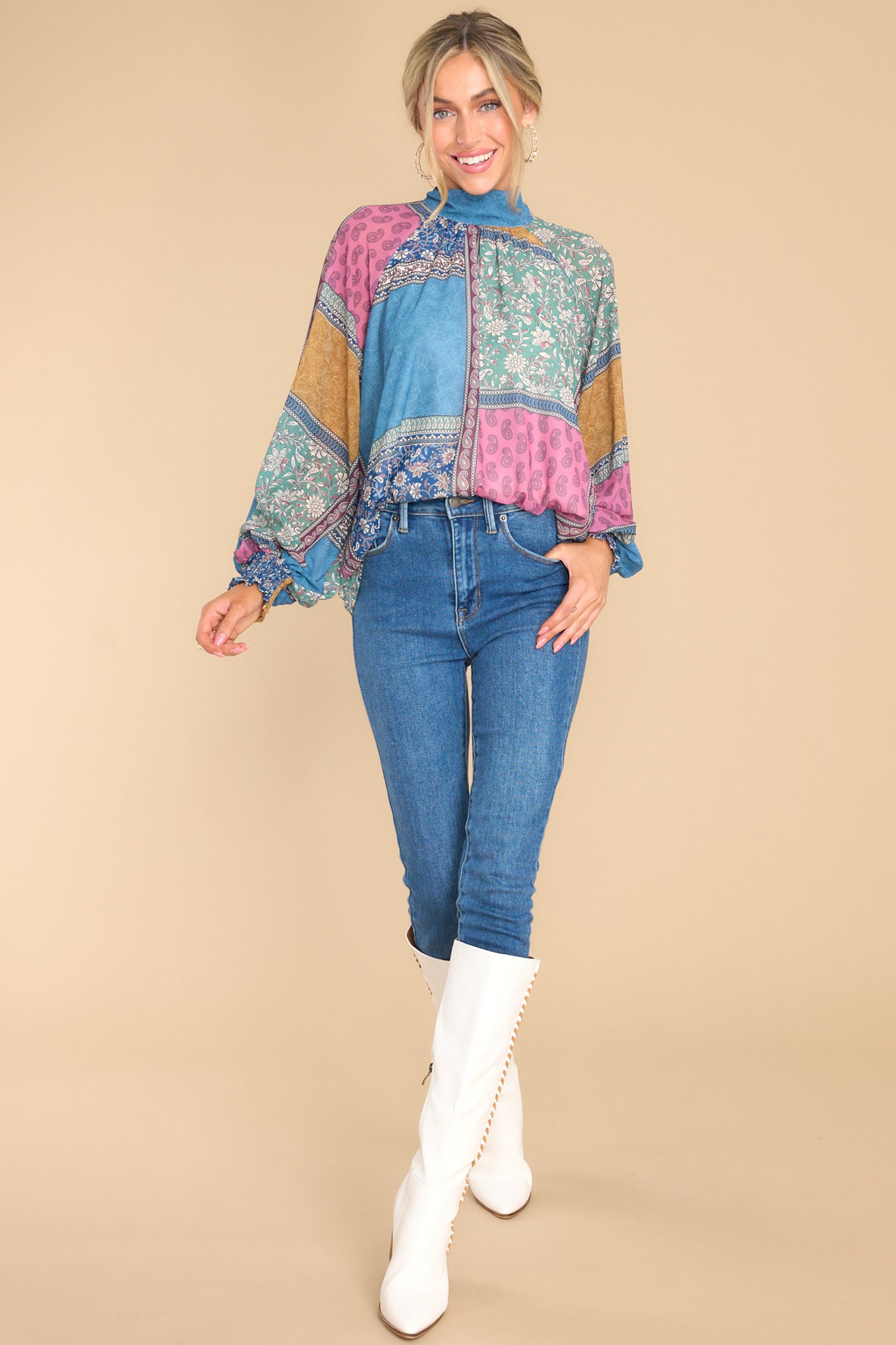 This multi-colored high-neck blouse features an adjustable self-tie around the neck, a small keyhole backing closed by a button loop closure, balloon sleeves with elastic cuffs, and a patchwork style design.