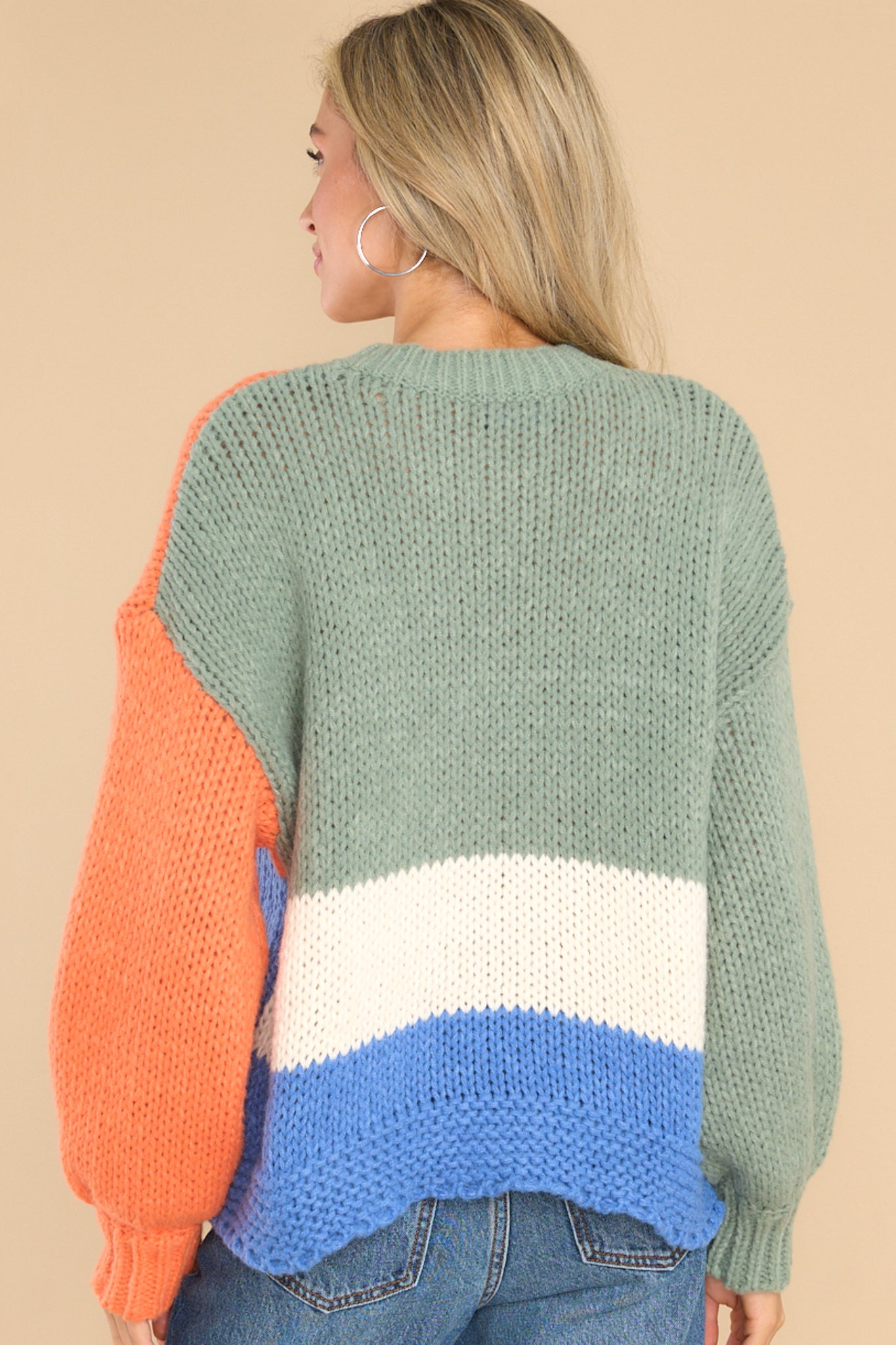 Back view of  this sweater that features a round neckline, long sleeves, a chunky knit design, and a colorblock pattern.