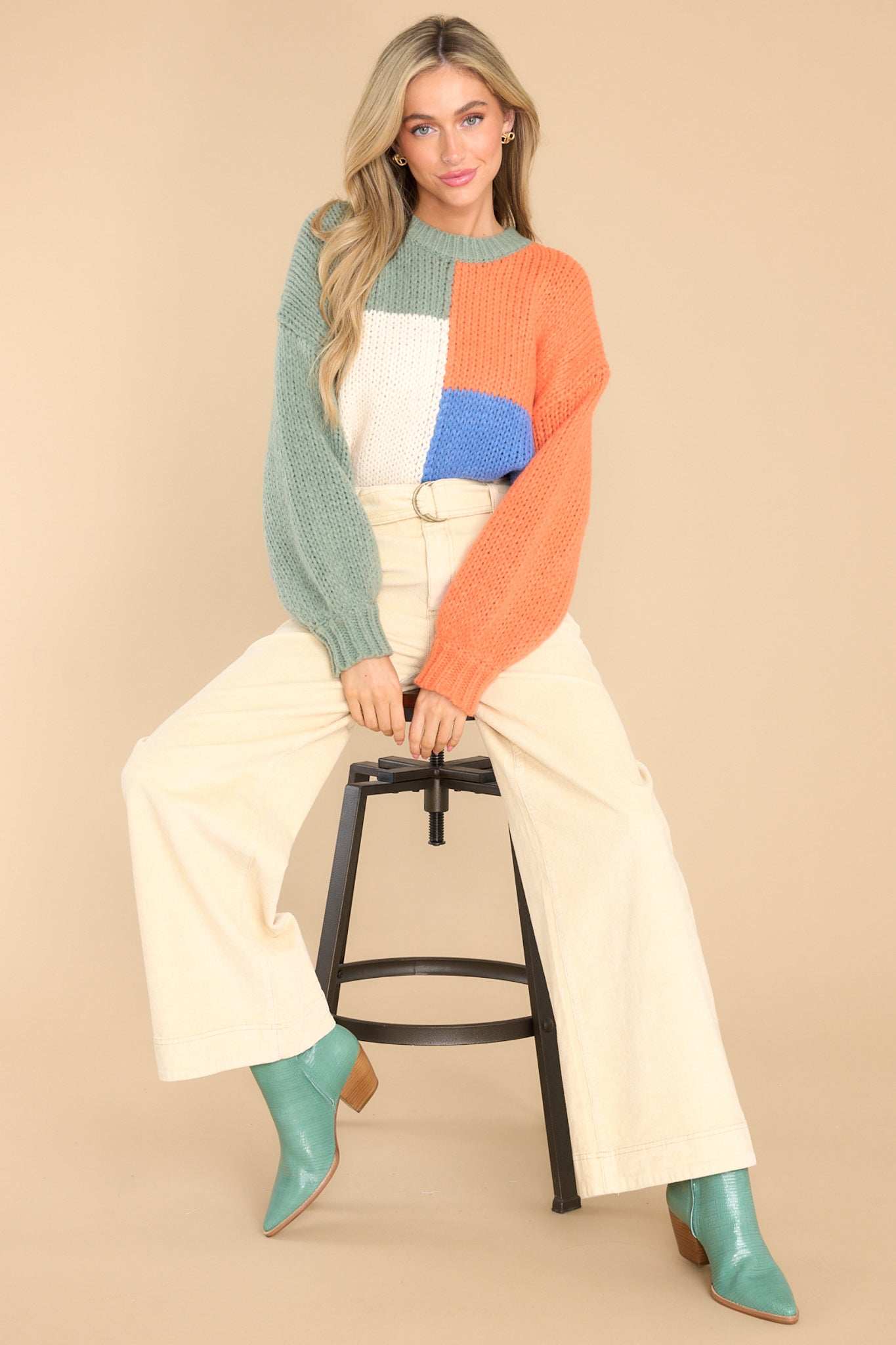 This multi-colored sweater features a round neckline, long sleeves, a chunky knit design, and a colorblock pattern.