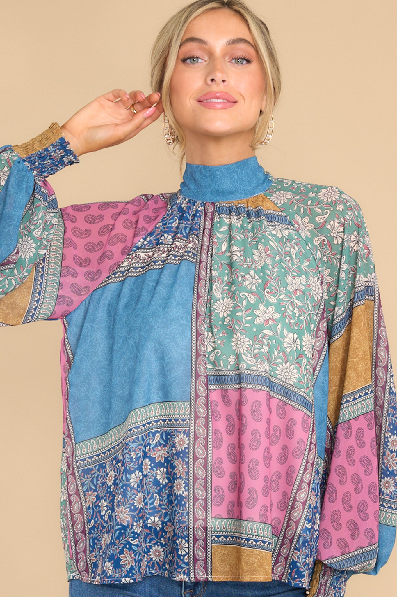 Close up view of this blouse that showcases a bohemian pattern in shades of pink, orange, and blue.