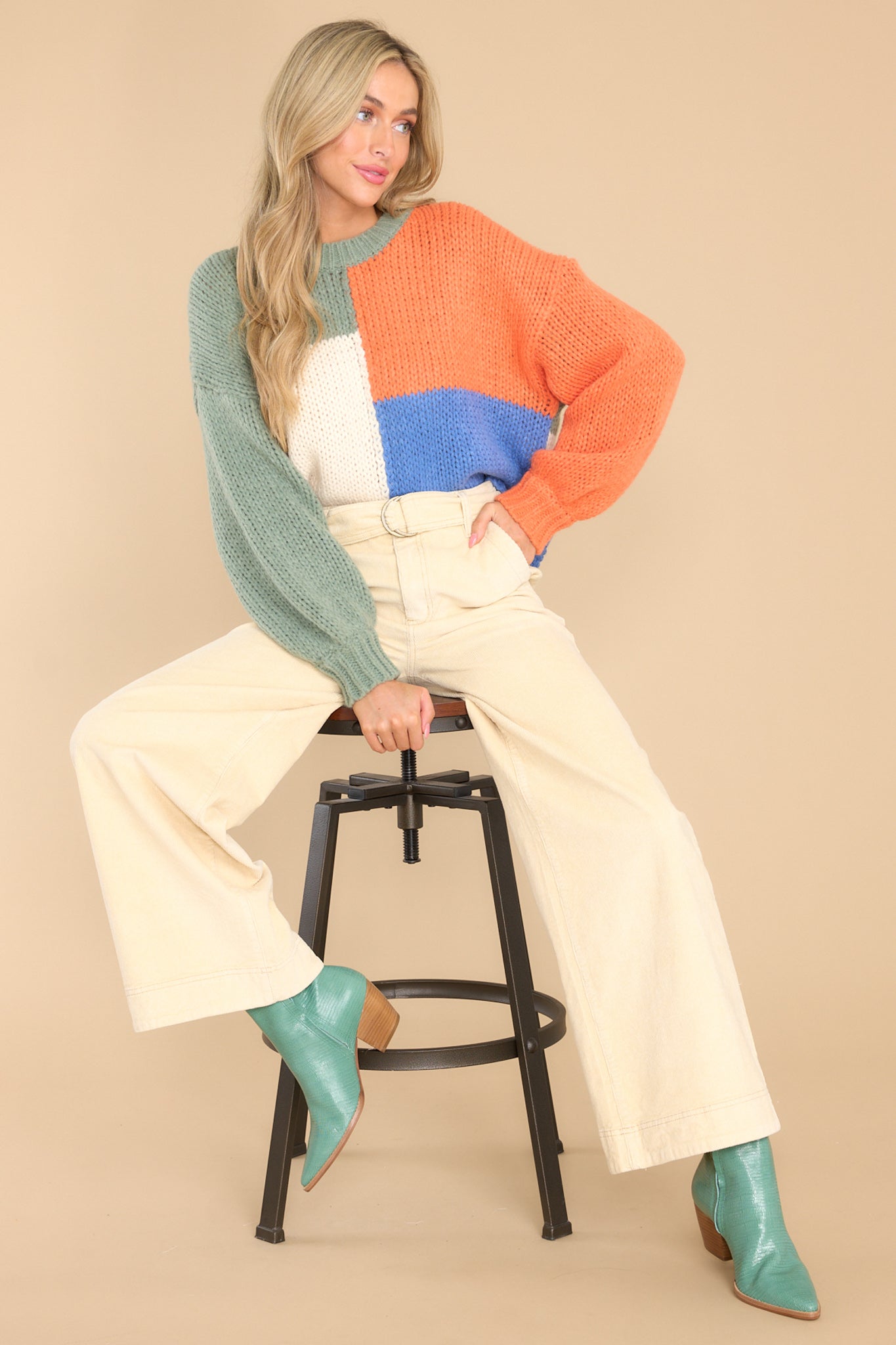 Full body view of  this sweater that features a round neckline, long sleeves, a chunky knit design, and a colorblock pattern.