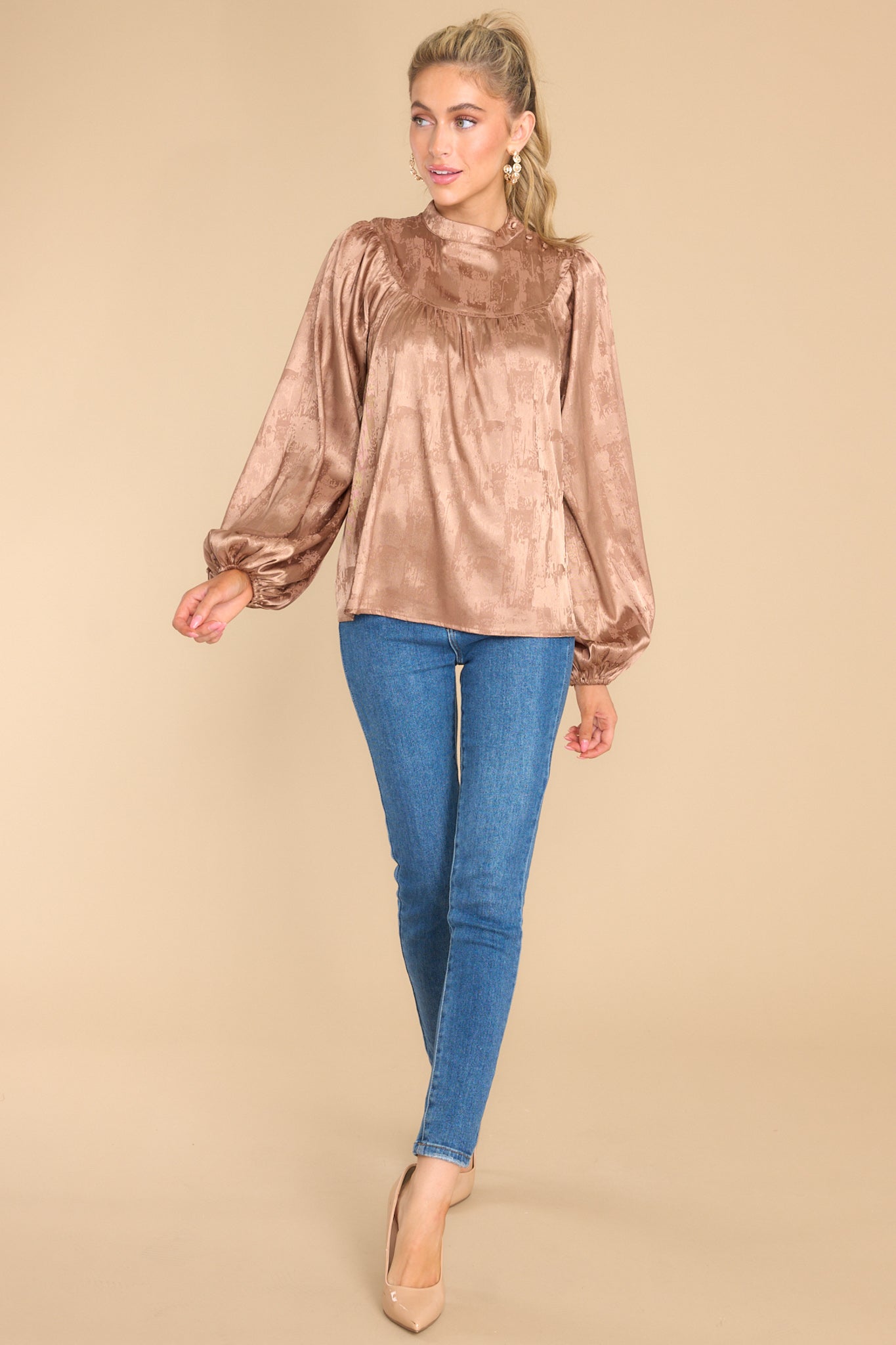 This light brown shiny satin-like top features a high neckline with buttons on the side, balloon sleeves, and elastic cuffs.