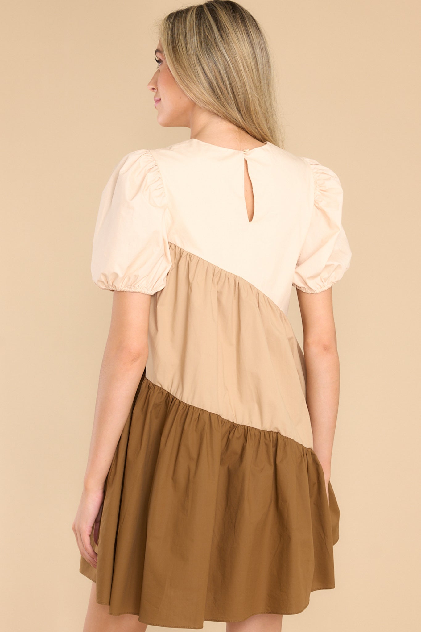 Back view of this dress that features a crew neckline, a keyhole with a button closure on the back, elastic cuffed puffy sleeves, and pockets at the hips.