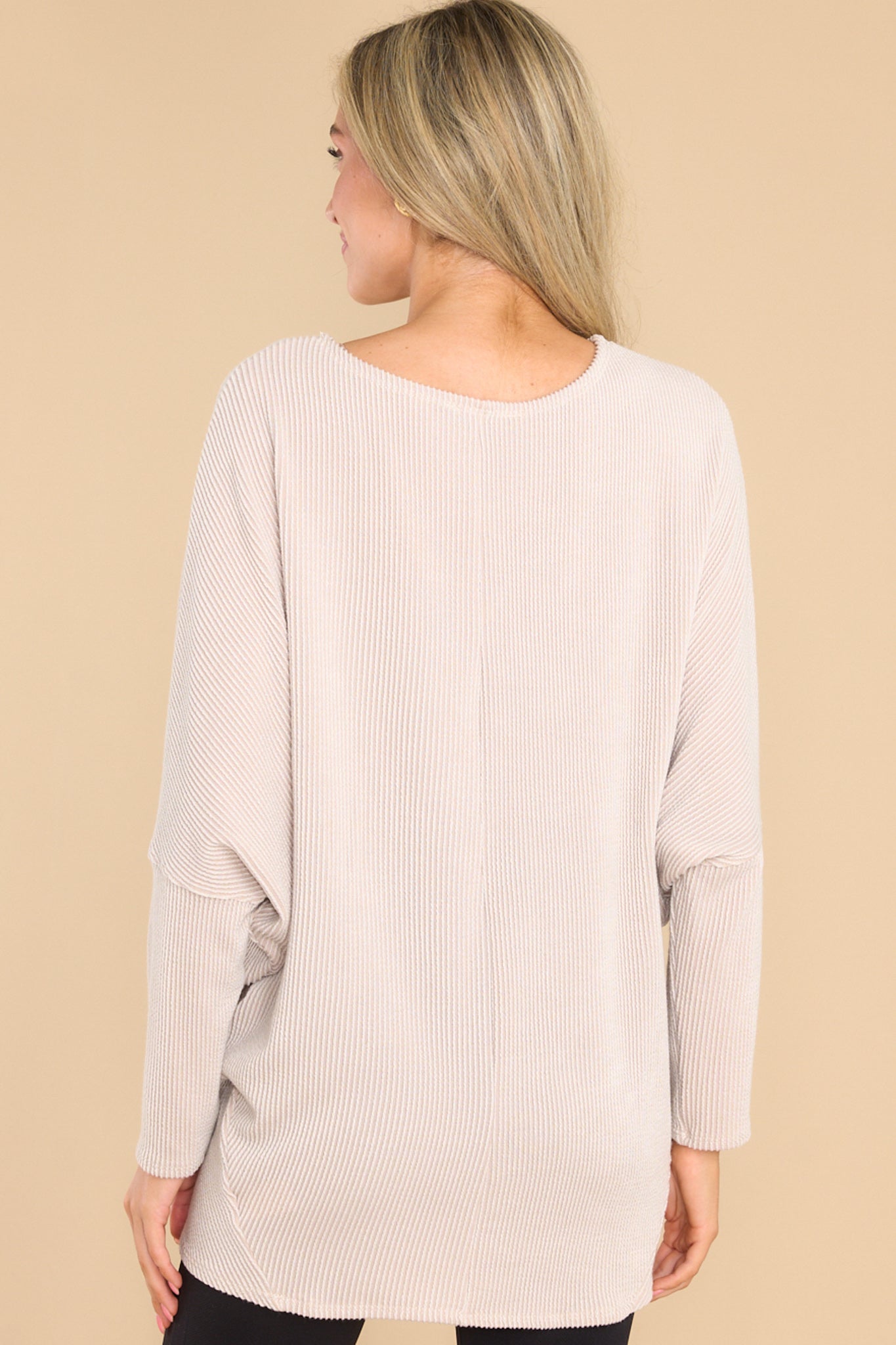 Back view of this pullover top that features a round neckline, long dolman sleeves, and a slight high low hem line.