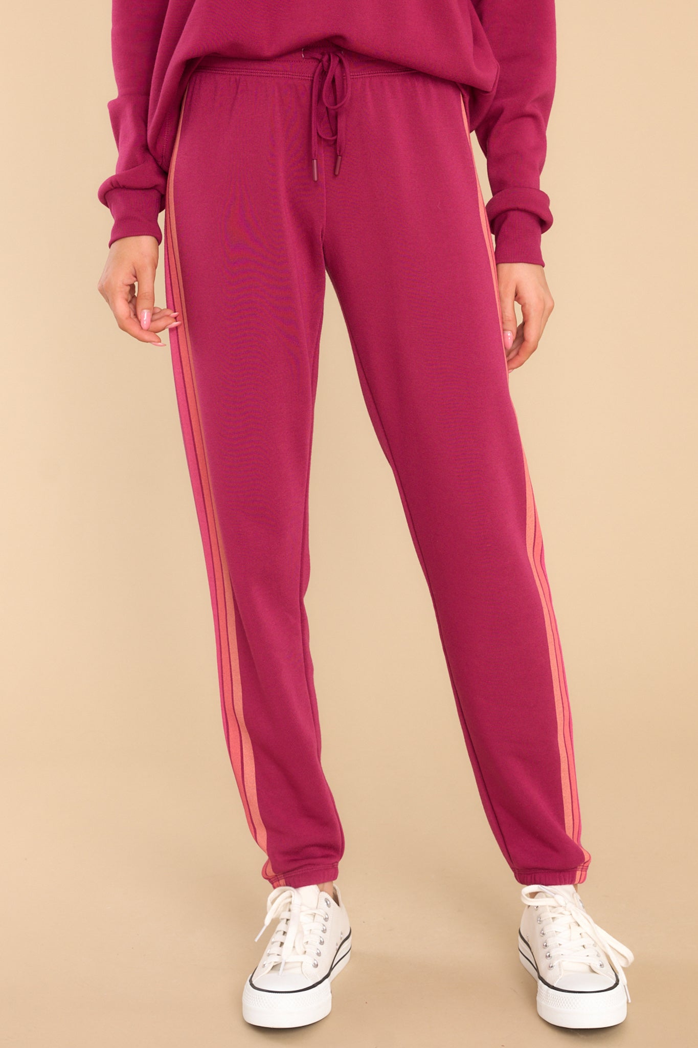 Close up view of these pants that feature an elastic waist, an adjustable self-tie drawstring, elastic cuffs at the ankles, and stripes down the side.