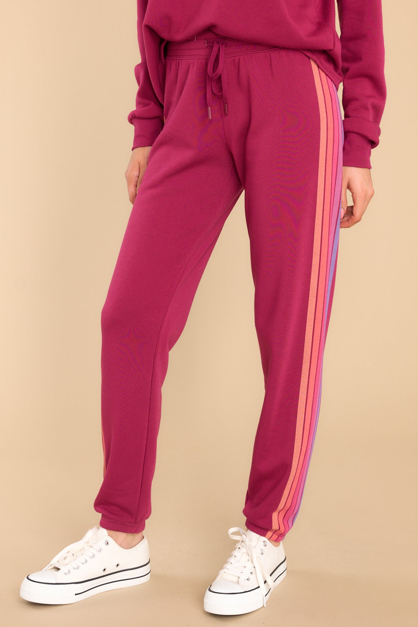 These raspberry colored pants feature an elastic waist, an adjustable self-tie drawstring, elastic cuffs at the ankles, and stripes down the side.