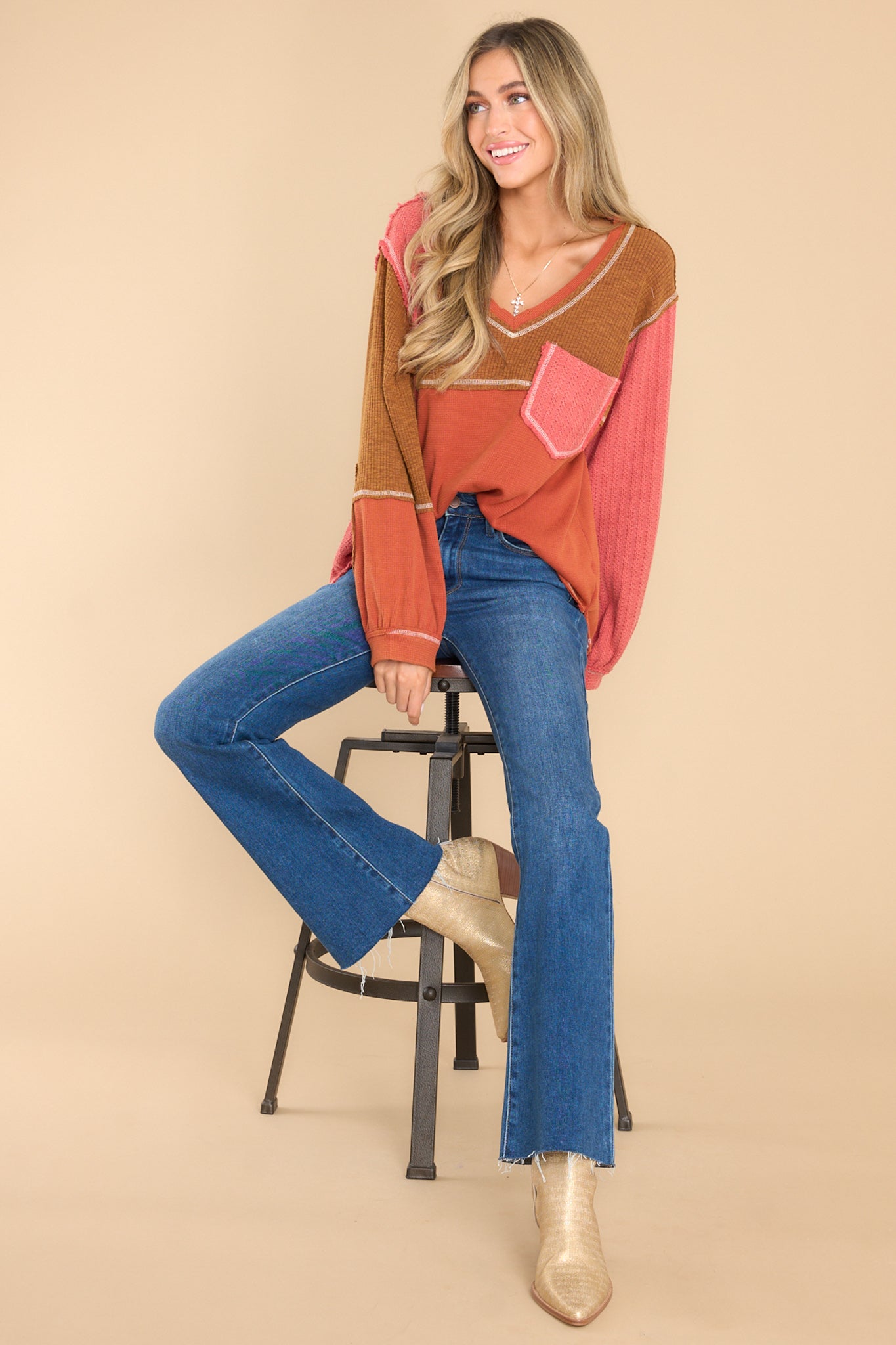 This multi-colored top features a v-neckline, a patchwork design, a breast pocket, and cuffed long sleeves.