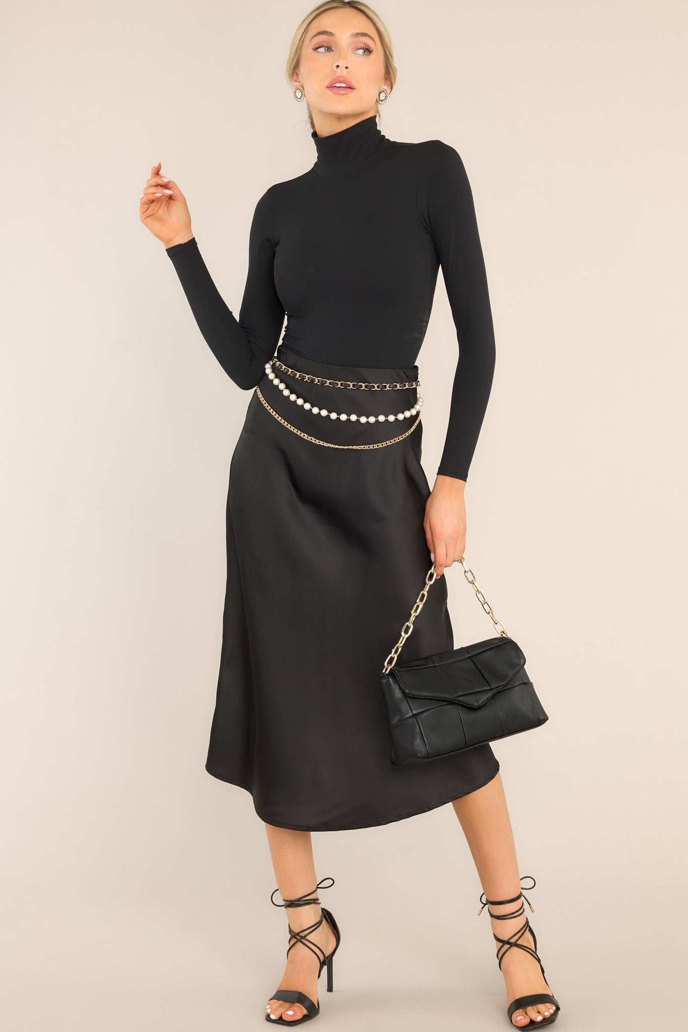 This all black skirt features an elastic waistband, a side zipper closure, a long, flowy skirt, and a satin finish.