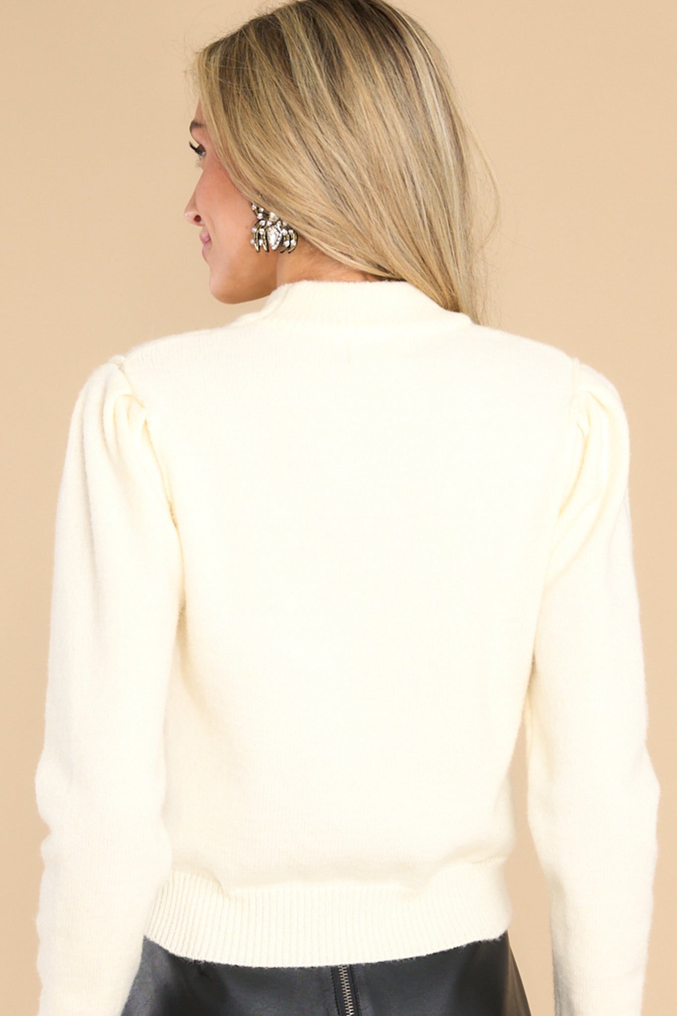 Back view of  this sweater that features a high neckline, cuffed long sleeves, and a festive sequin design.