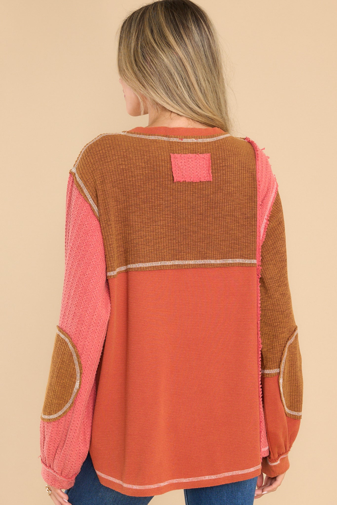 Back view of this top that features a v-neckline, a patchwork design, a breast pocket, and cuffed long sleeves.