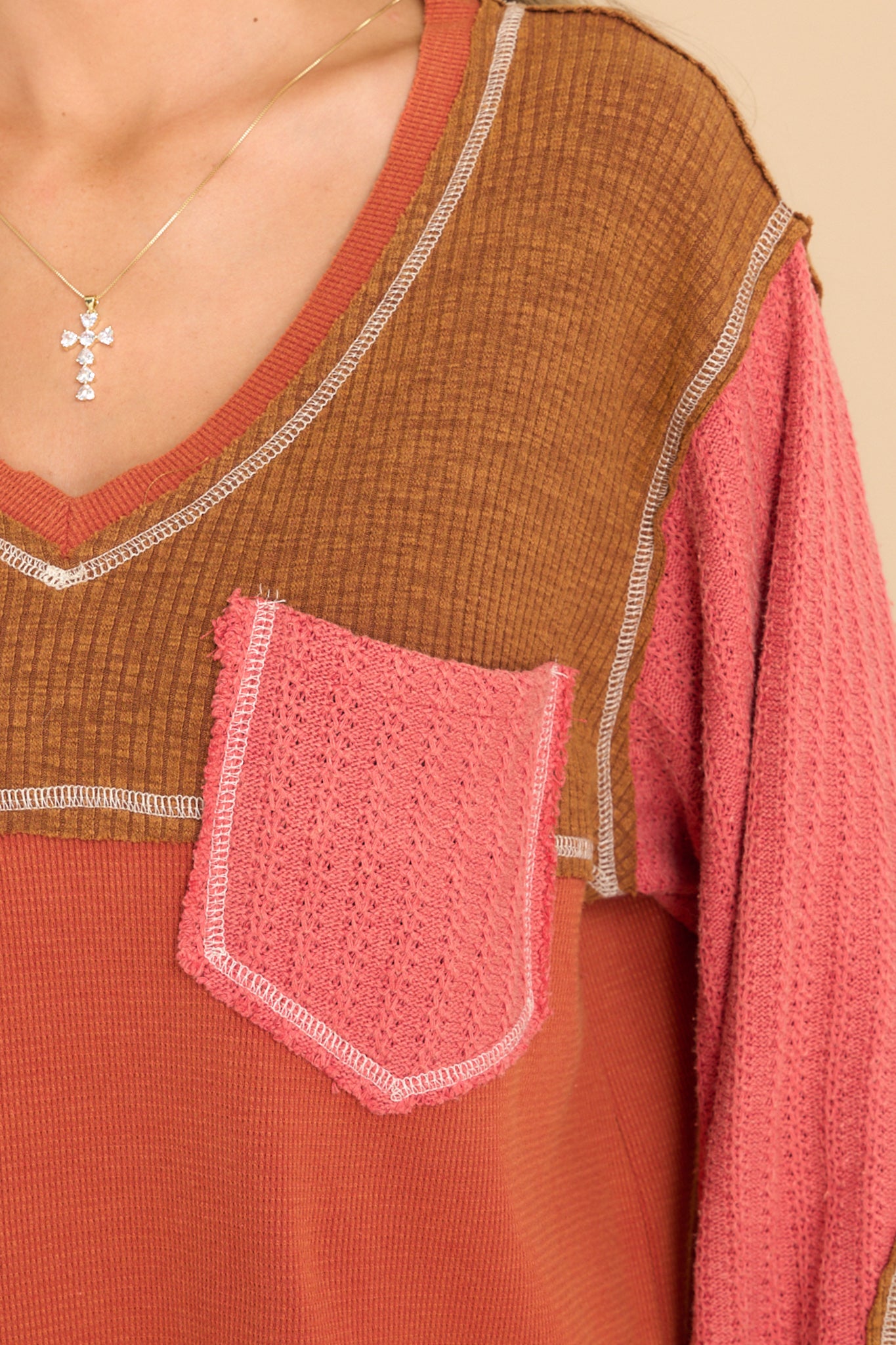 Close up view of this top that features a v-neckline, a patchwork design, a breast pocket, and cuffed long sleeves.