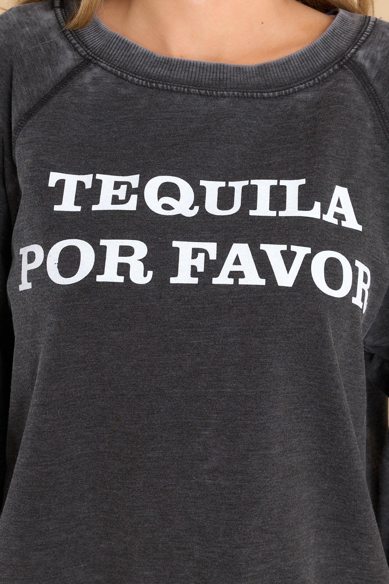 Close up view of this sweatshirt that features a round neckline, long sleeves with ribbed cuffs, a ribbed bottom hem, and tequila-themed graphic lettering on the front and back.