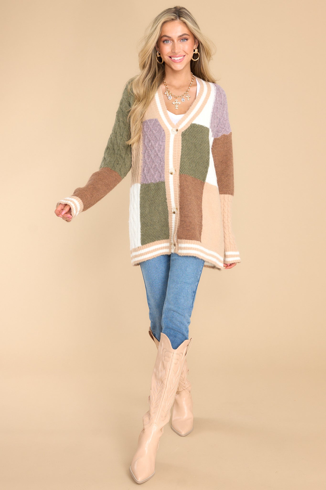 Full body view of this cardigan that features a v-neckline, functional buttons down the front, stripe detailing along the hem and cuffs, cable knit detailing, and a soft, knit material throughout.