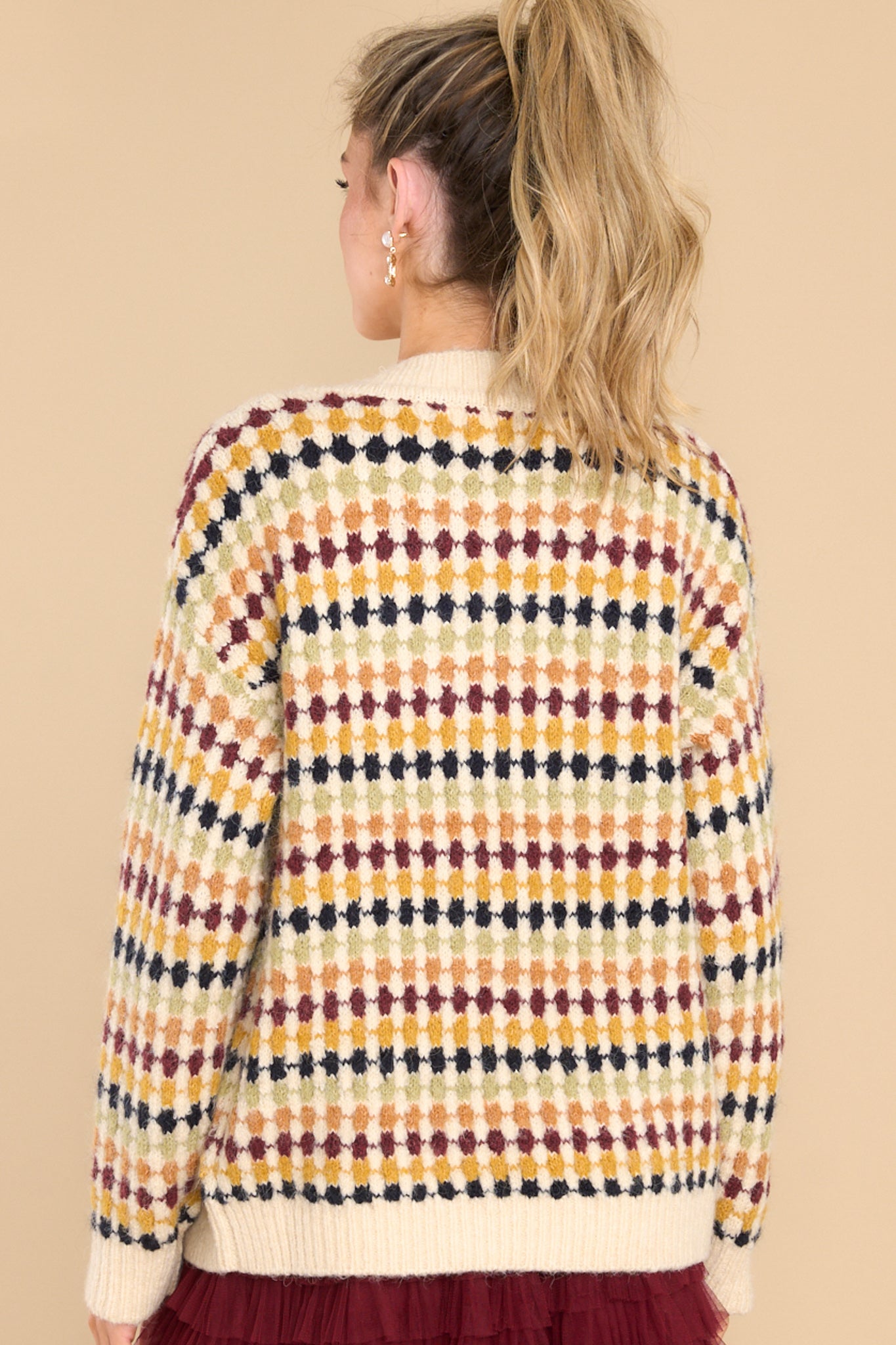 Back view of this cardigan that features a v-neckline, four functional buttons down the front, a ribbed hem, cuffed sleeves, and a fun pattern.