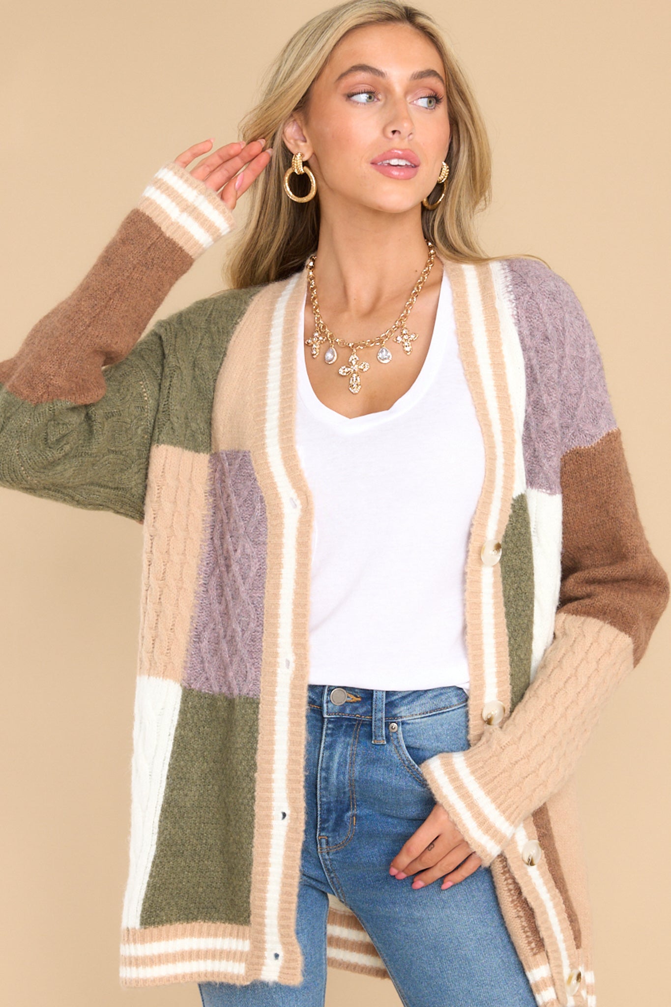 This multi-colored color-block cardigan features a v-neckline, functional buttons down the front, stripe detailing along the hem and cuffs, cable knit detailing, and a soft, knit material throughout.