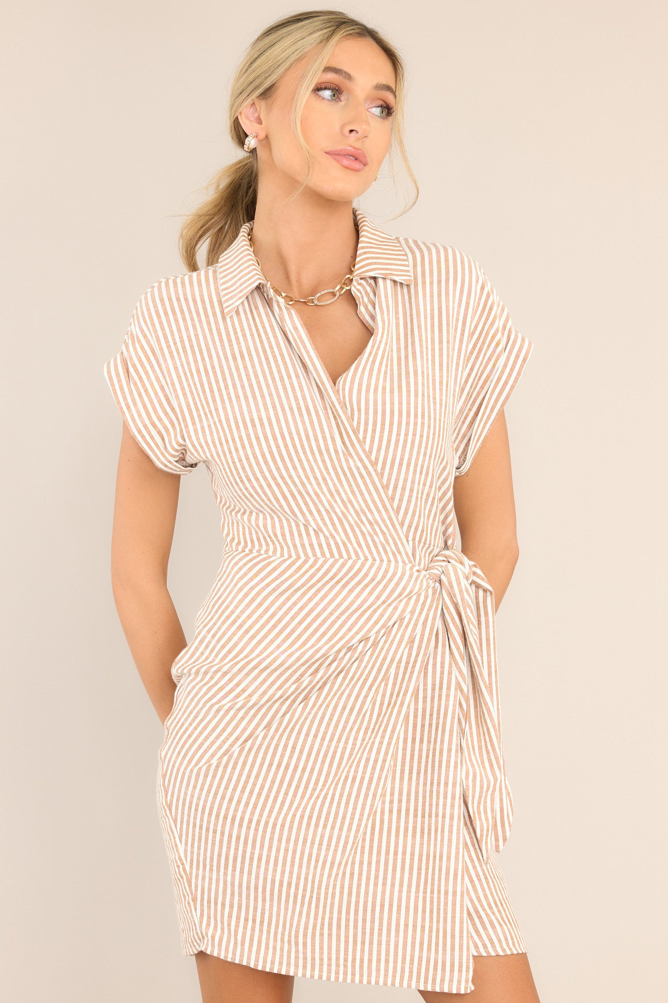 Front view of this dress that features a collared v-neckline, a wrap design with a self-tie feature at the waist, and cuffed short sleeves. 