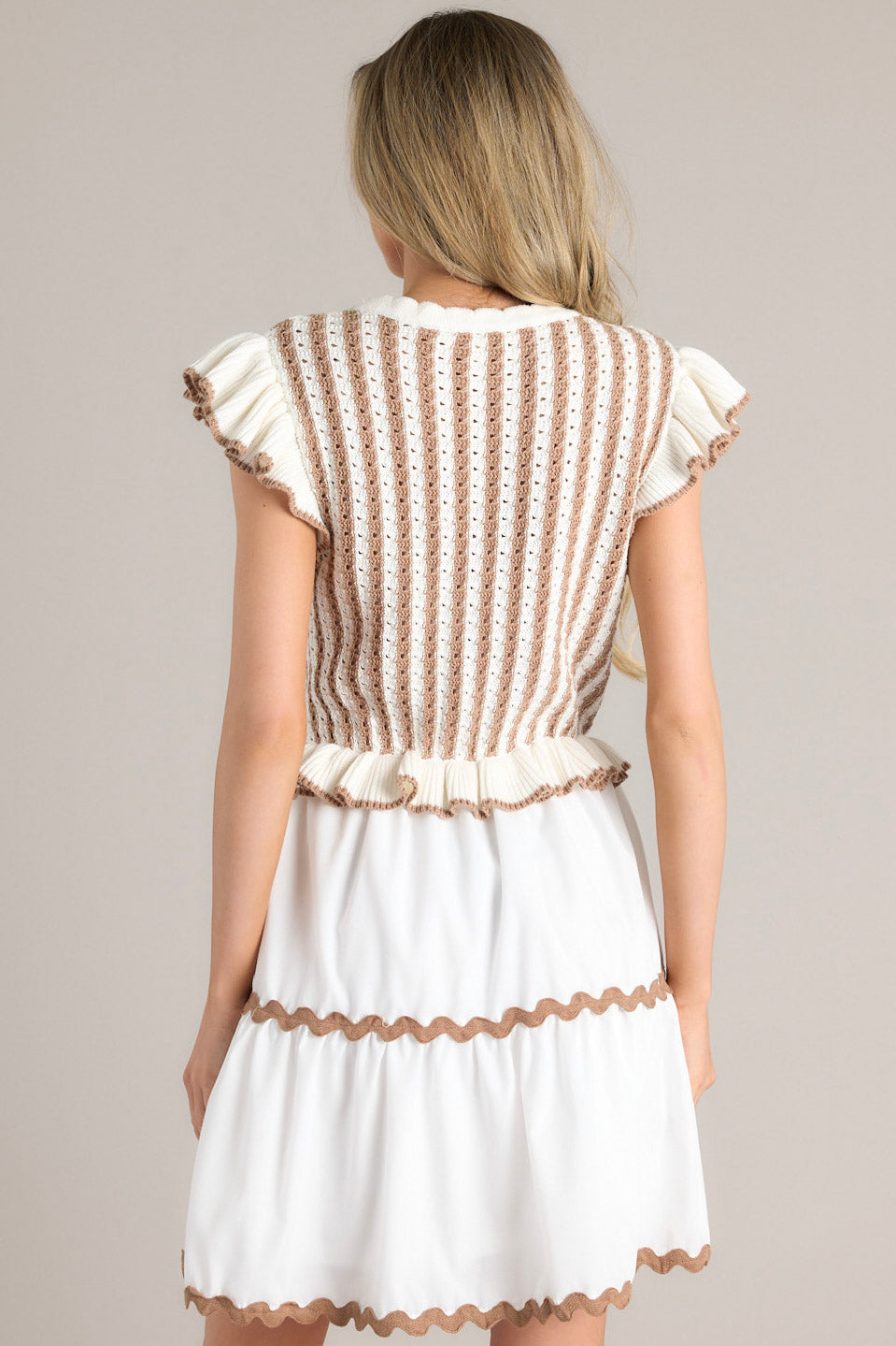 Back view of this dress that features a scalloped crew neckline, a striped knitted bodice, a ruffled waistline, functional pockets, scalloped detailing, a scalloped hemline, and ruffled sleeves.