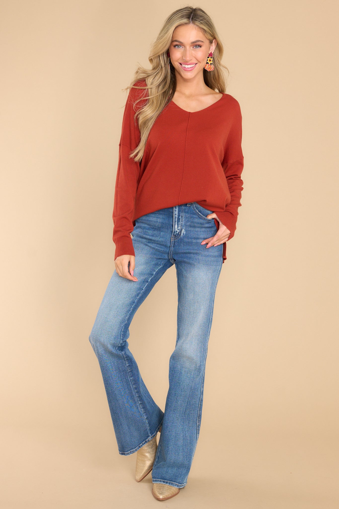 This dark orange sweater features a v-neckline and a high low hemline.