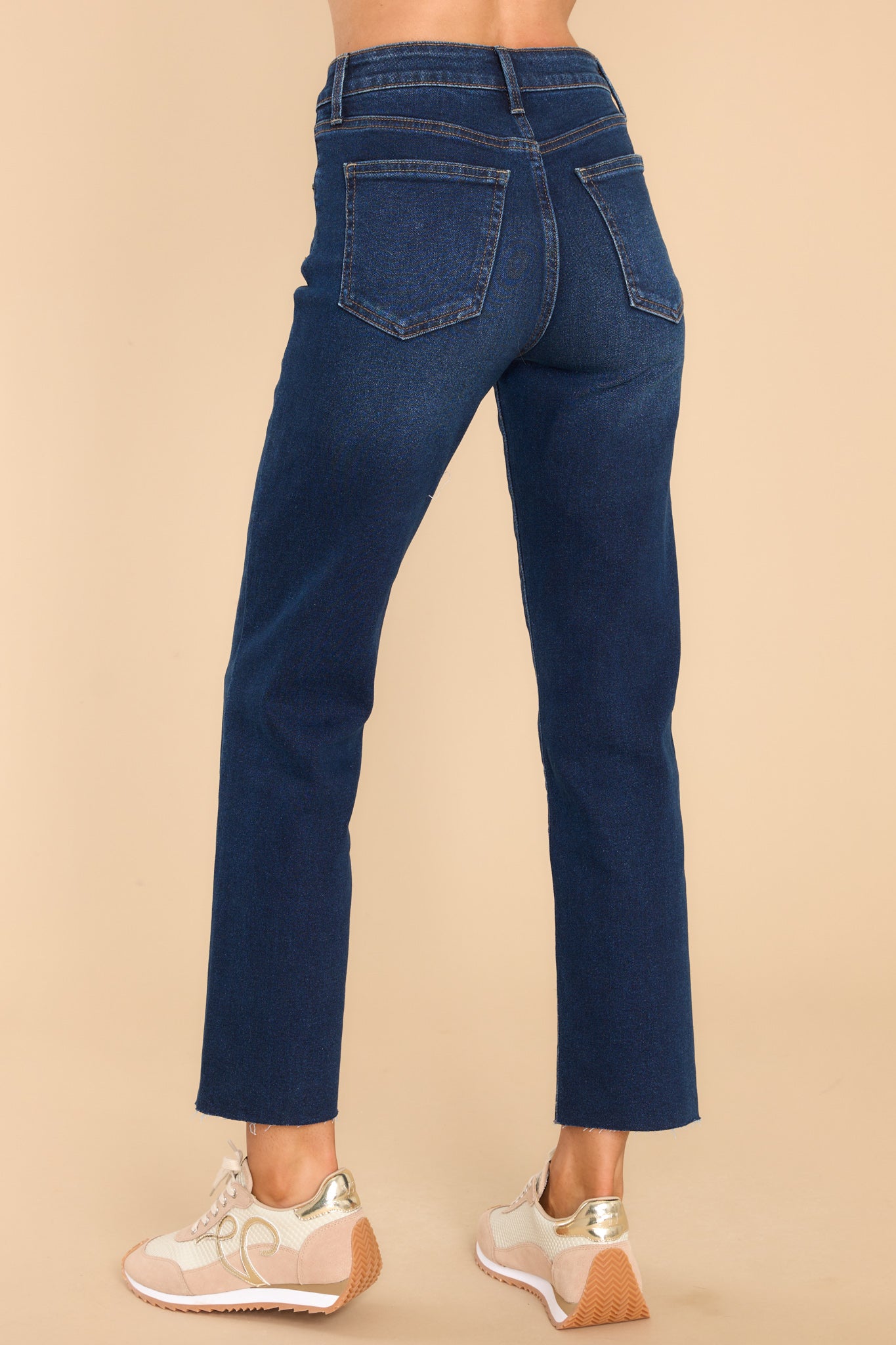 Back view of these jeans that feature a zipper down the front with one button closure, five functional pockets, a straight leg and a raw hem at the bottom.