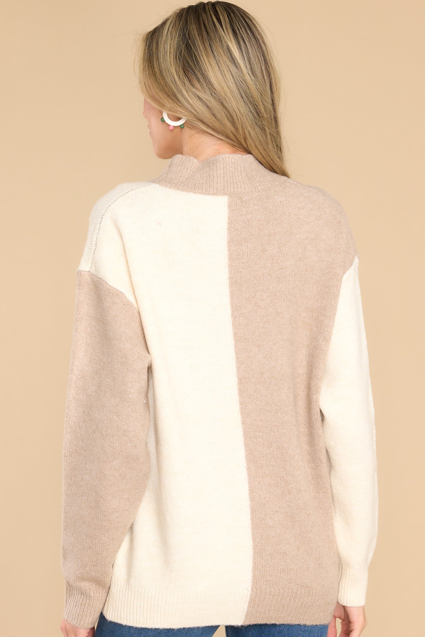 Back view of this sweater that features a high neckline, a two toned color pattern, and cuffed long sleeves.