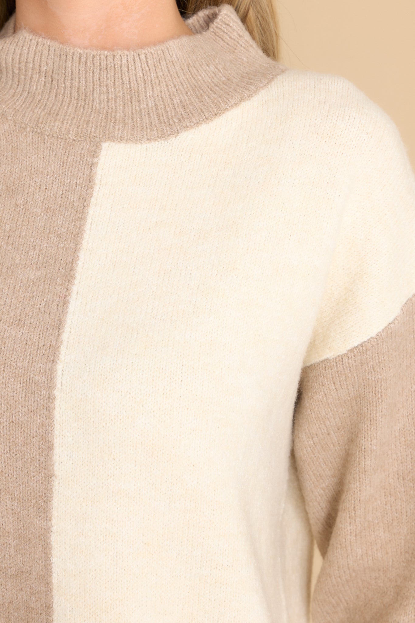 Close up view of this sweater that features a high neckline and a two toned color pattern in shades light brown and ivory.