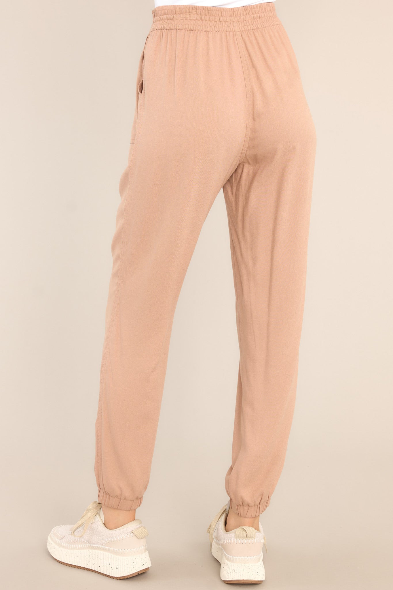 Back view of these joggers that feature an elastic waist with a self-tie drawstring, two functional waist pockets, an elastic ankle, and a lightweight breathable fabric.