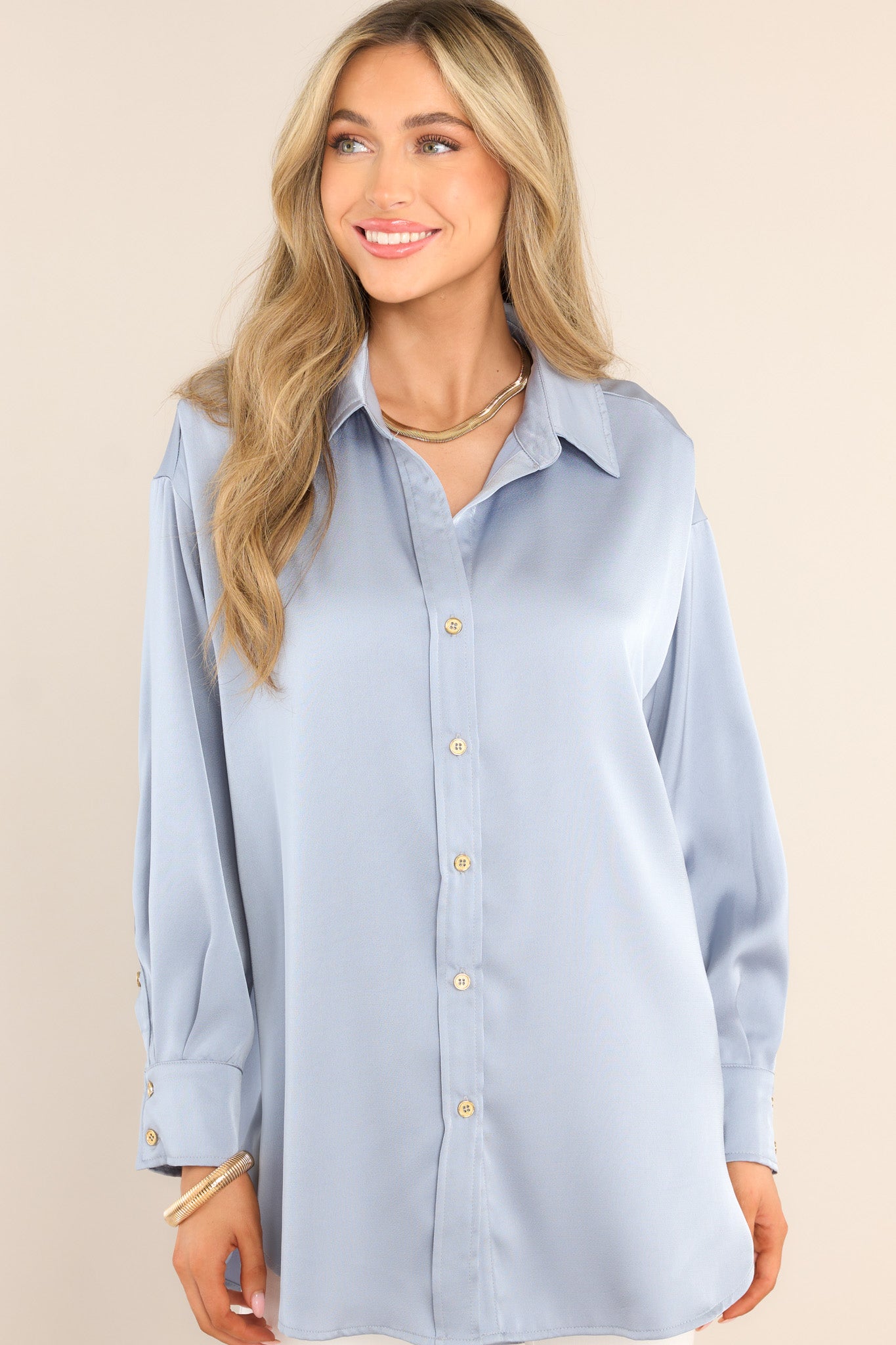 Front view of this top that features a collared neckline, functional gold buttons down the front, long sleeves with buttoned cuffs, and a round hemline.