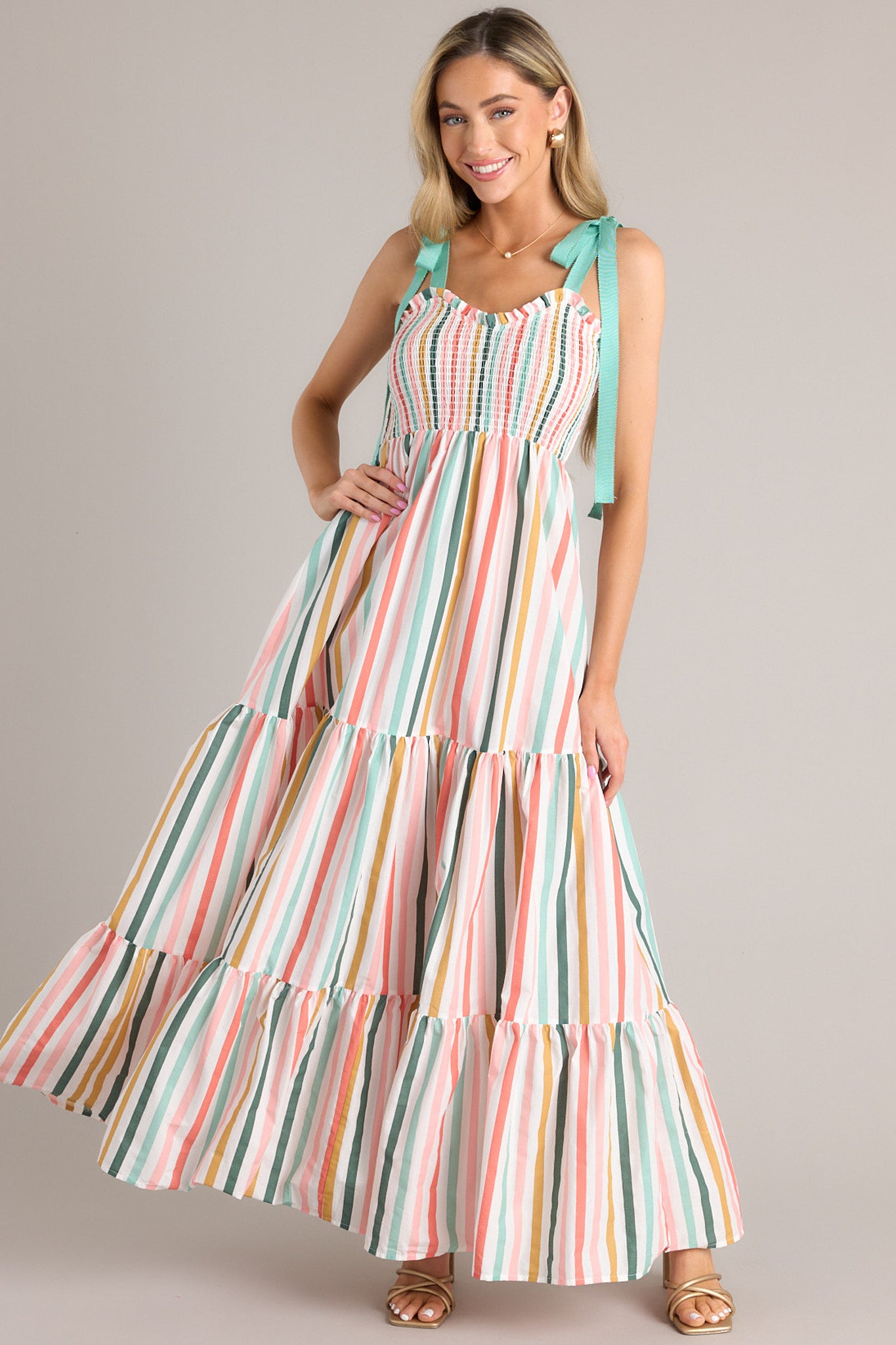 Front view of  this dress that features a v-neckline, adjustable self-tie straps, a smocked bust, and flowy tiers down the skirt.